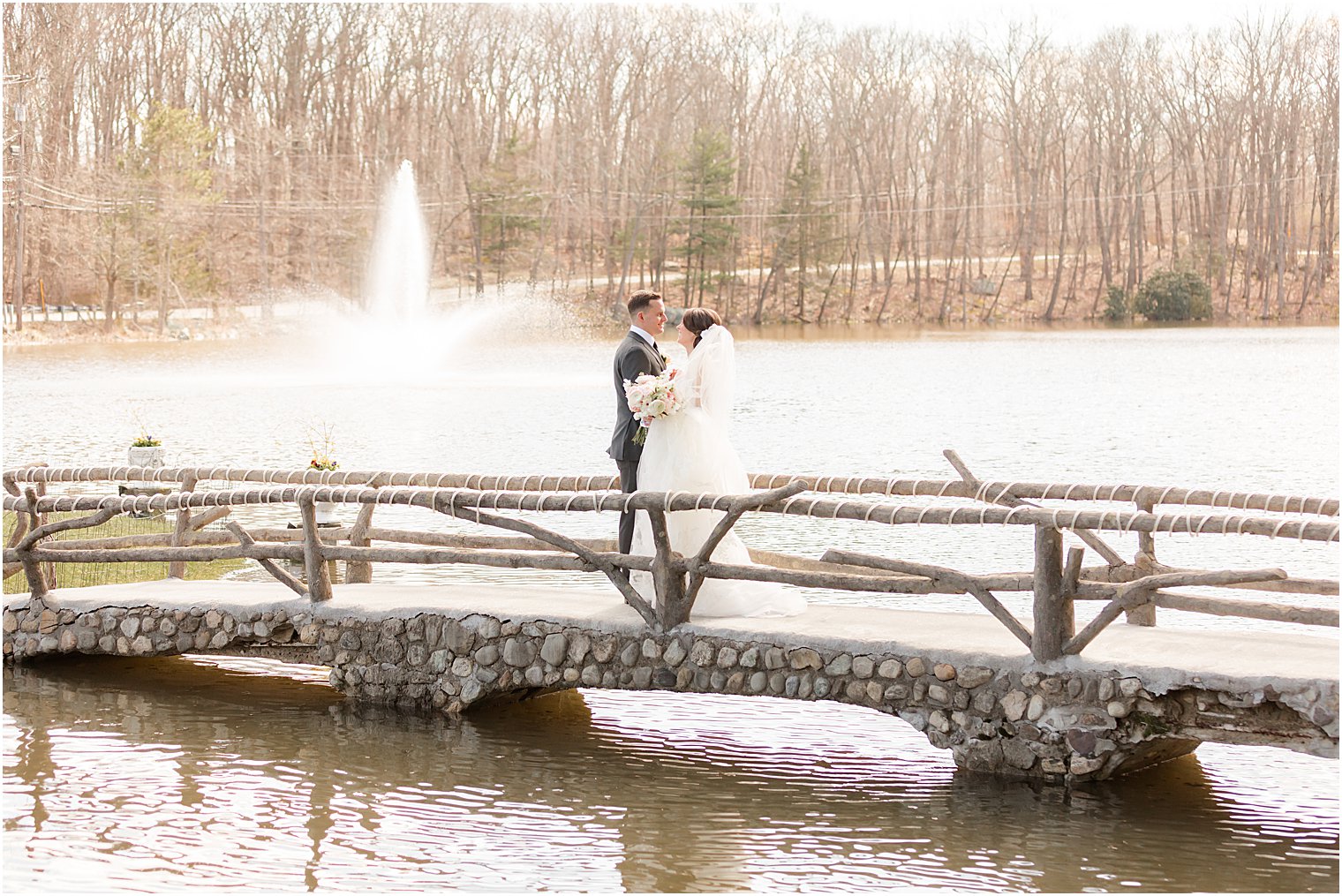 bride and groom hug on wooden bridge at The Refinery at Perona Farms