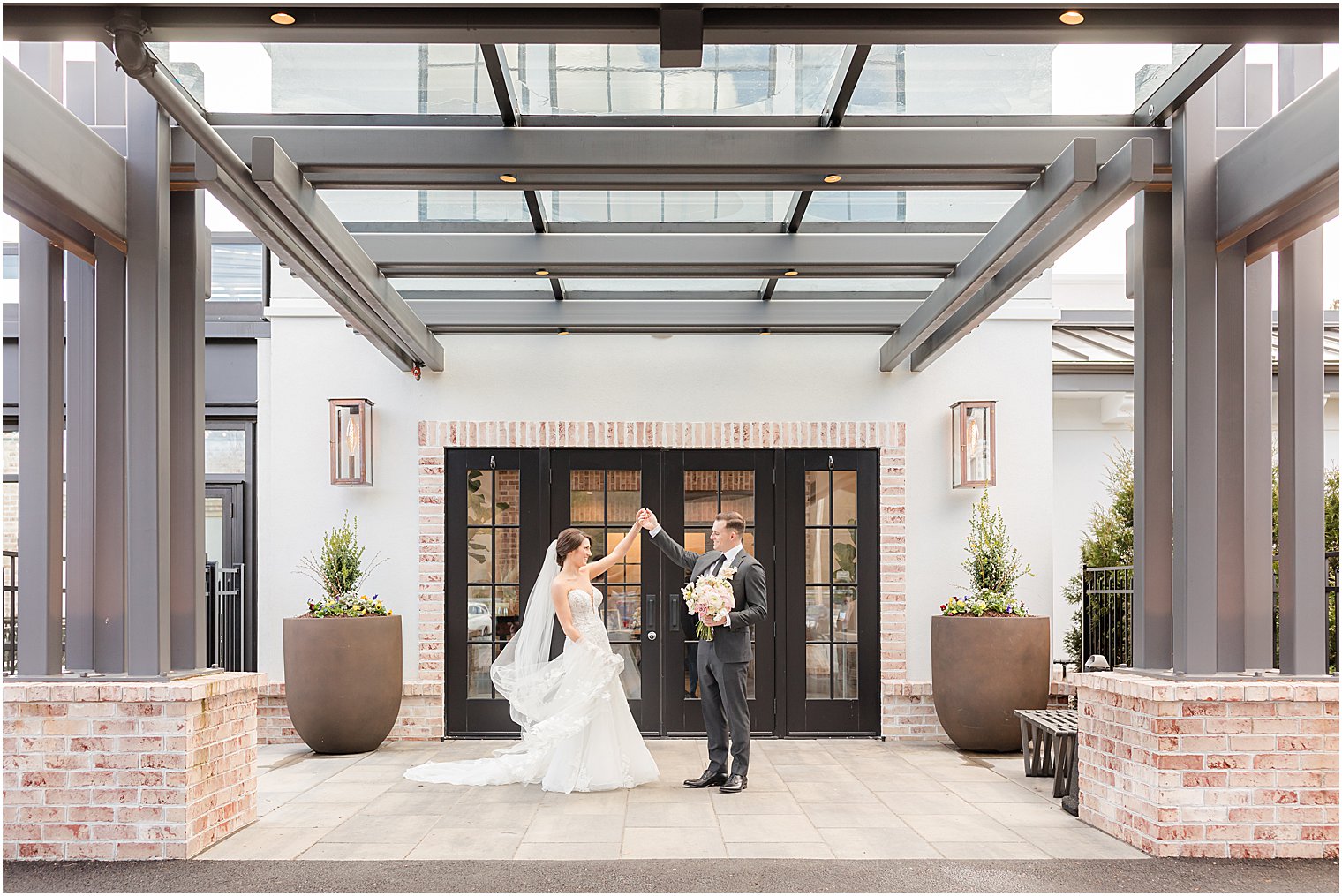 groom twirls bride outside the door of The Refinery at Perona Farms