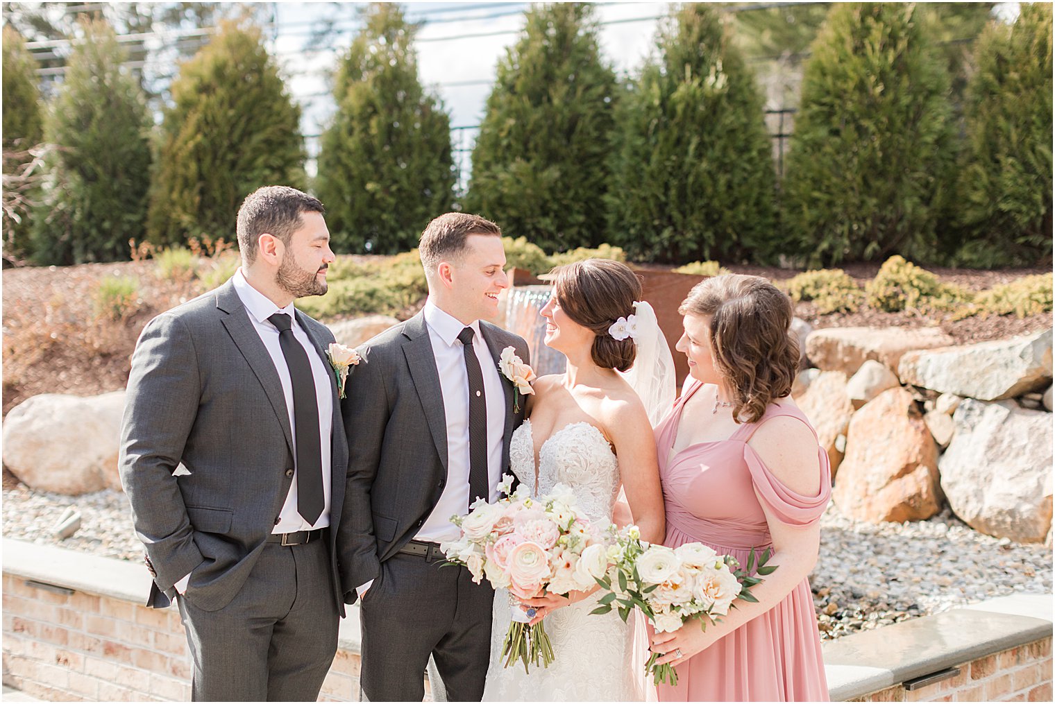 bride and groom stand with bridal party in grey and pink