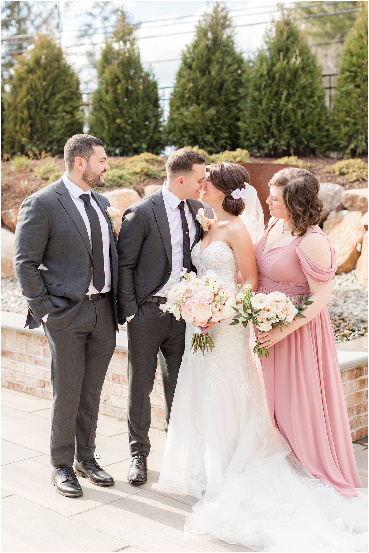 bride and groom kiss while bridesmaid and best man look on
