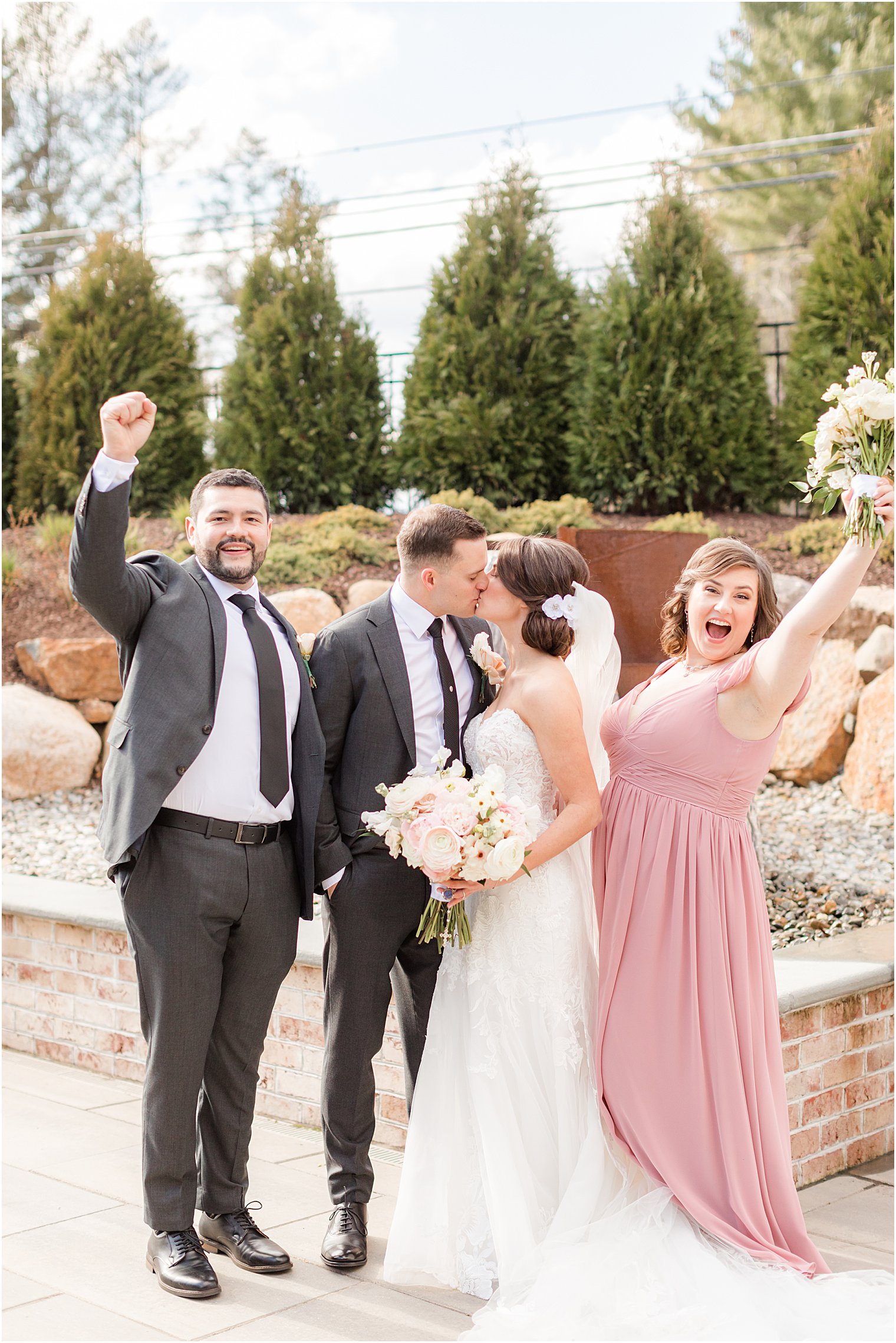best man and maid of honor cheer while bride and groom kiss