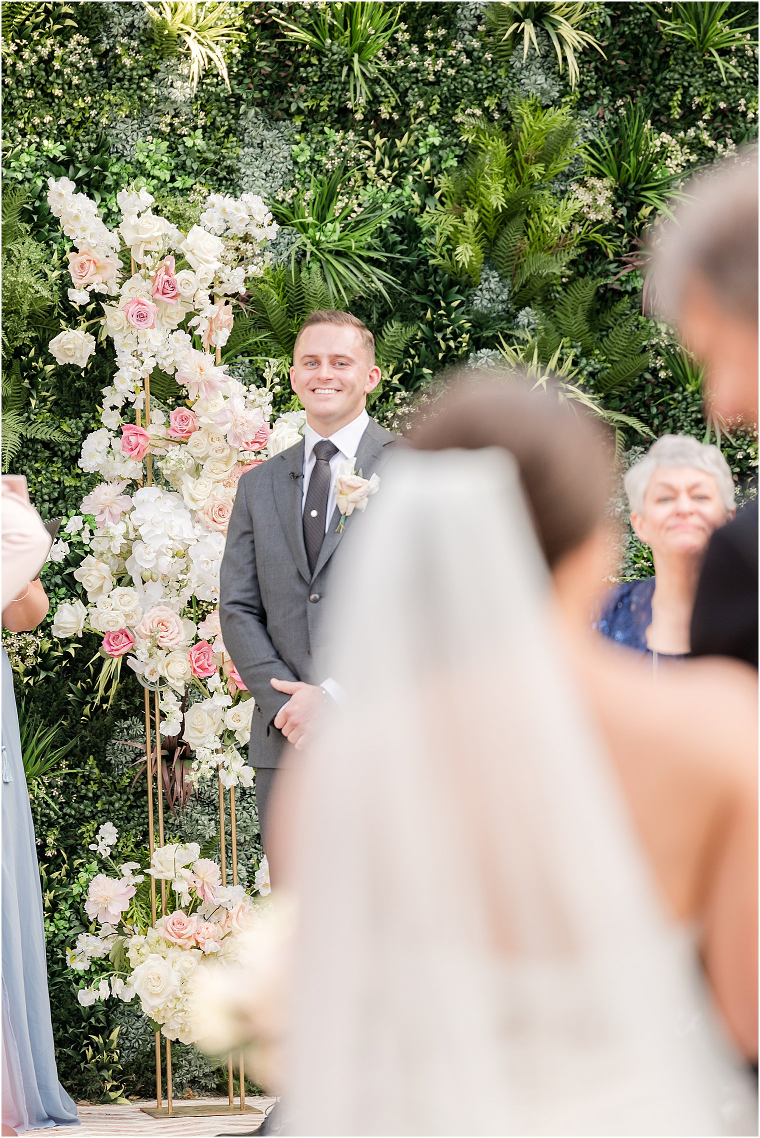 groom watches bride enter outdoor wedding ceremony in courtyard