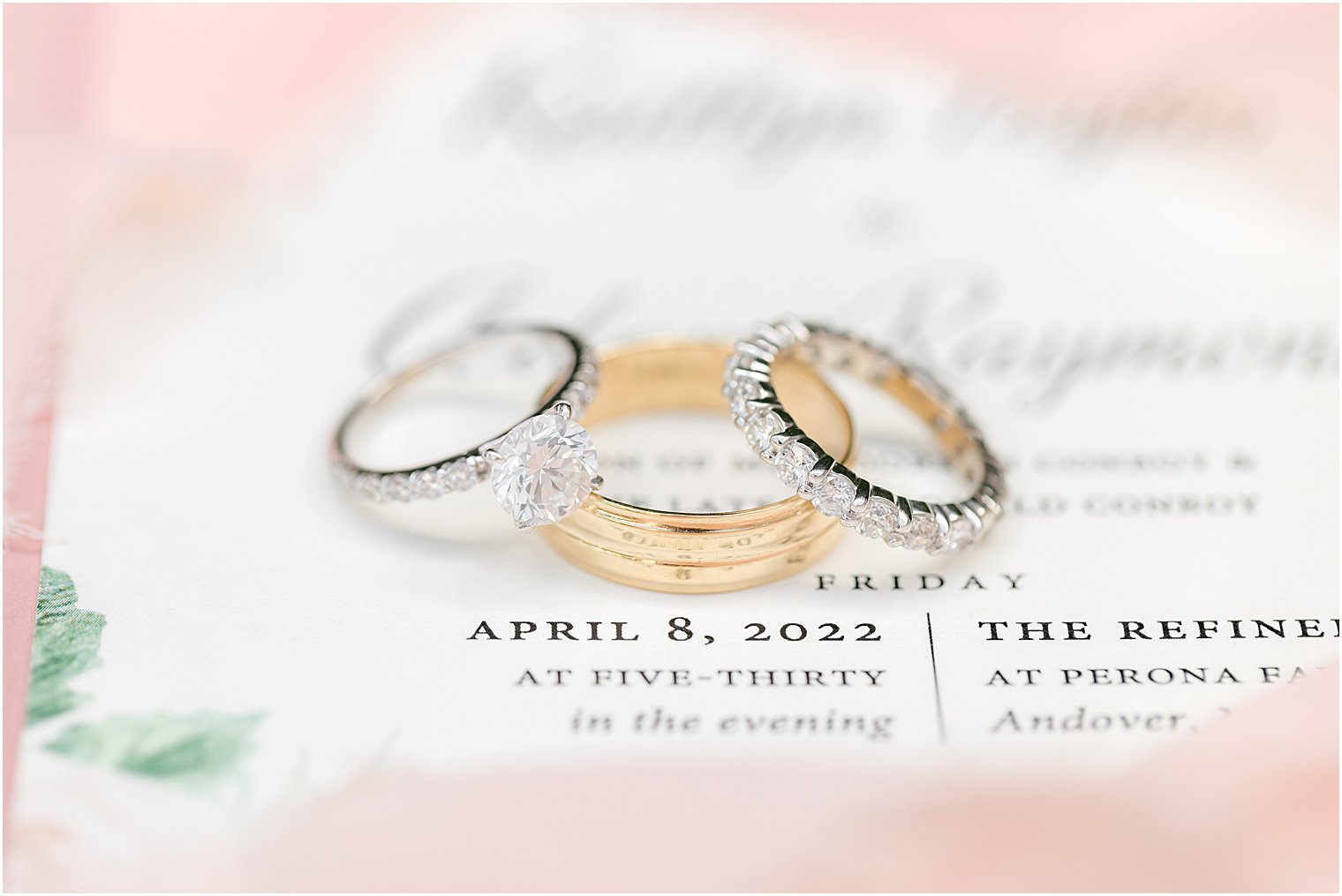 gold wedding bands rest on invitation for spring wedding