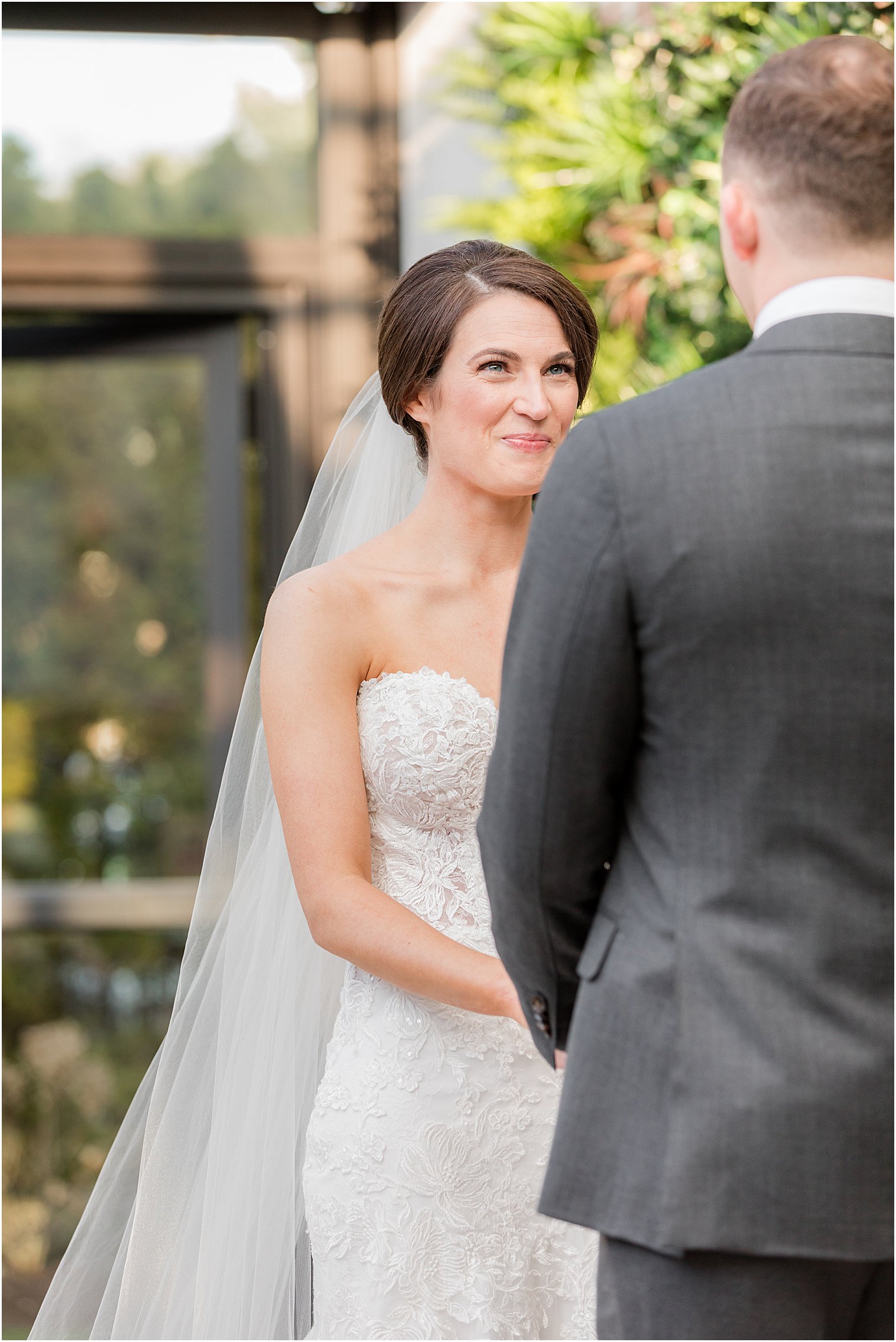 bride smiles at groom during outdoor wedding ceremony in courtyard