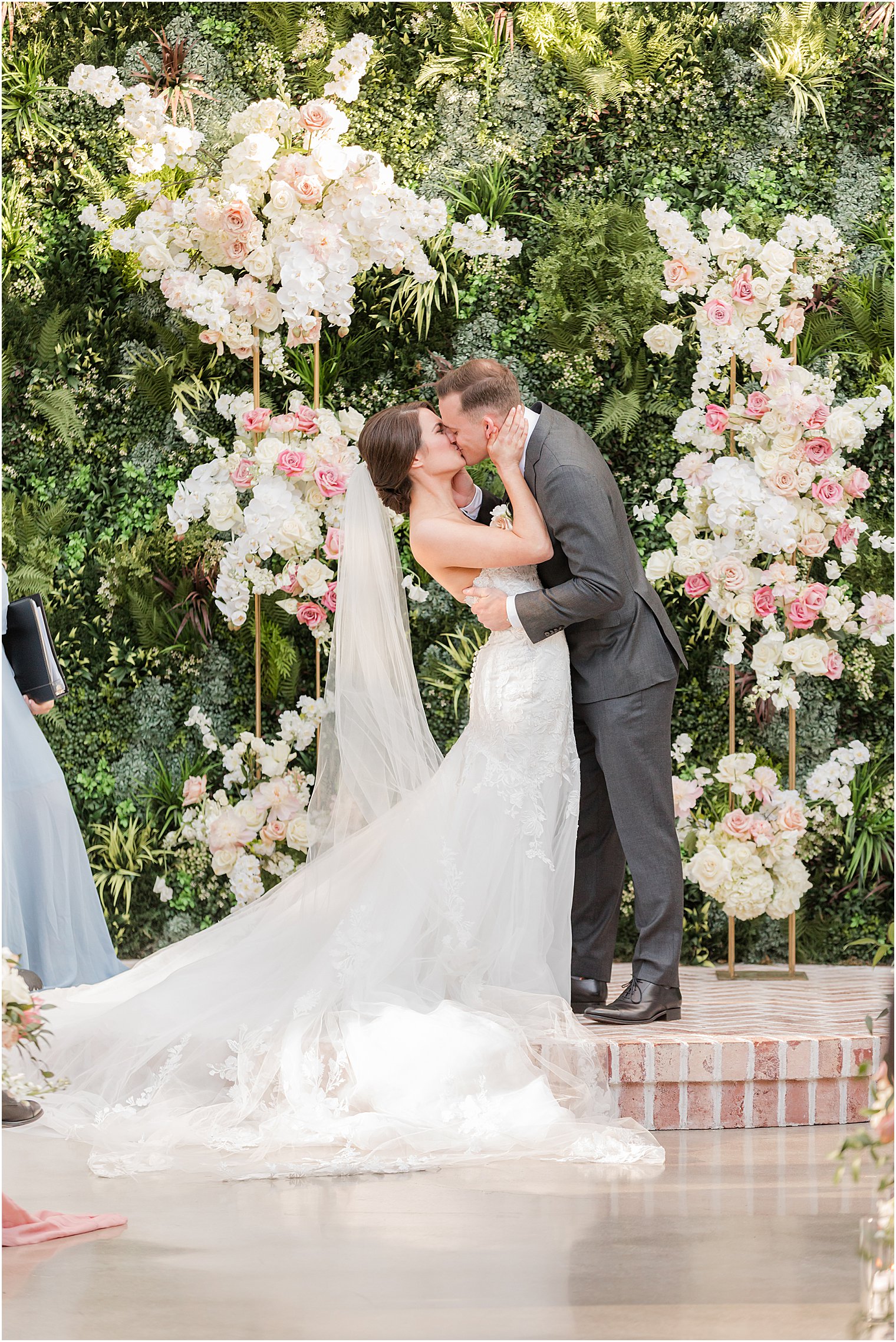 couple kisses on brick platform during outdoor wedding ceremony in courtyard