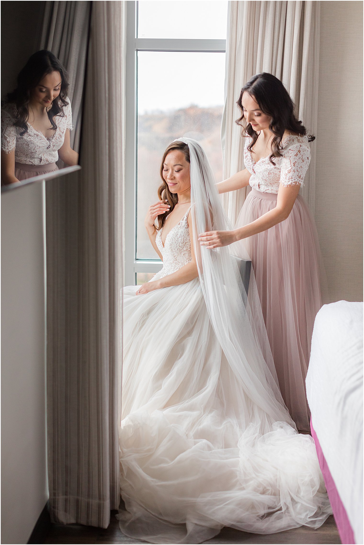 bridesmaid helps bride with veil during prep