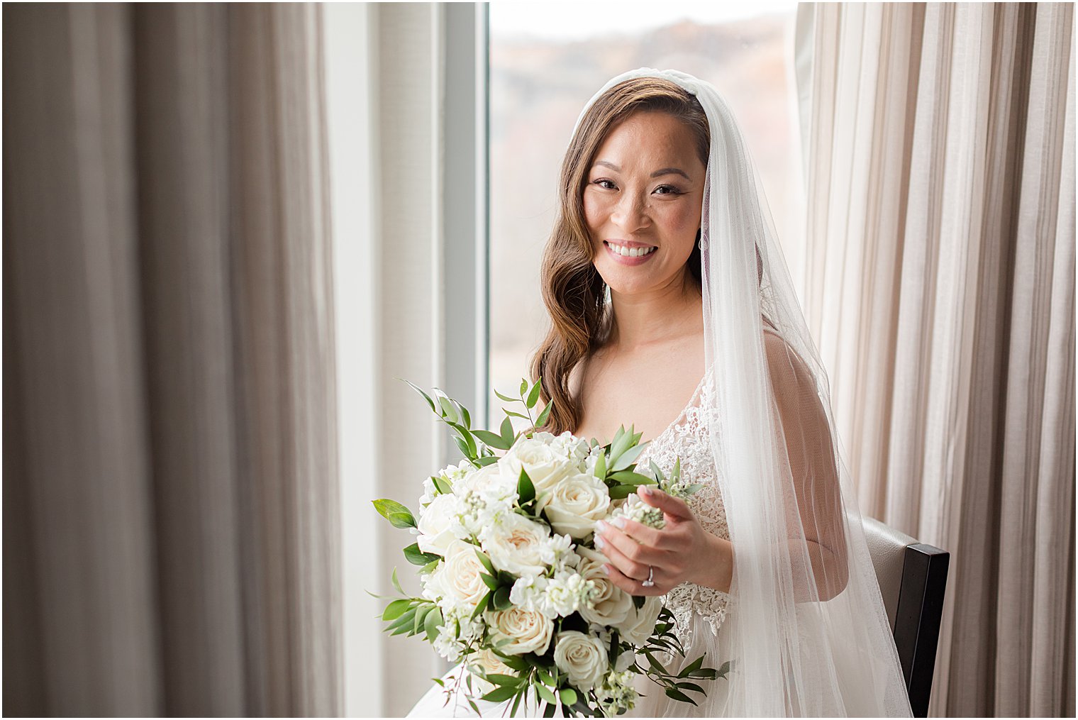 bride smiles holding bouquet of ivory roses