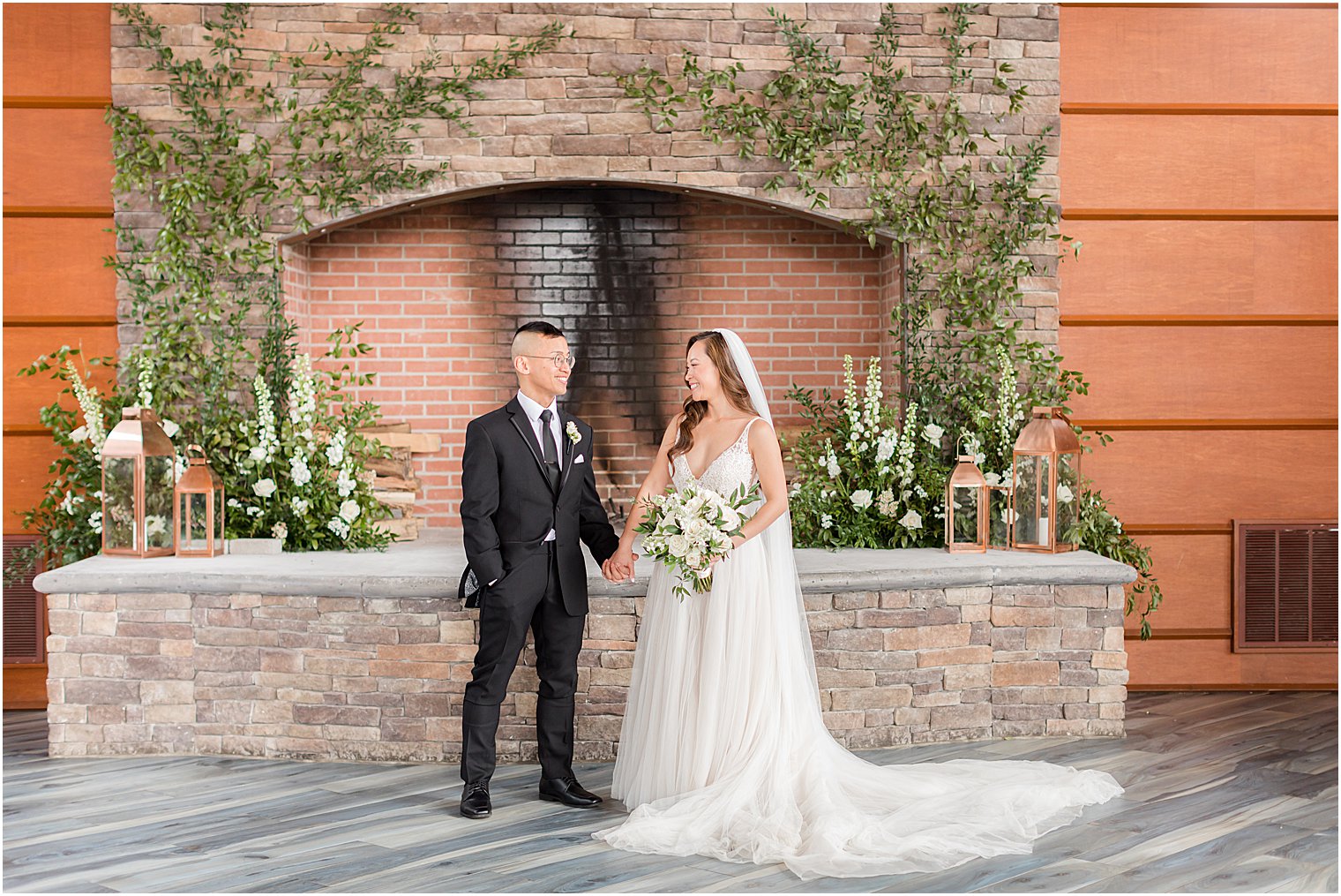 bride and groom hold hands by stone fireplace in New Jersey 