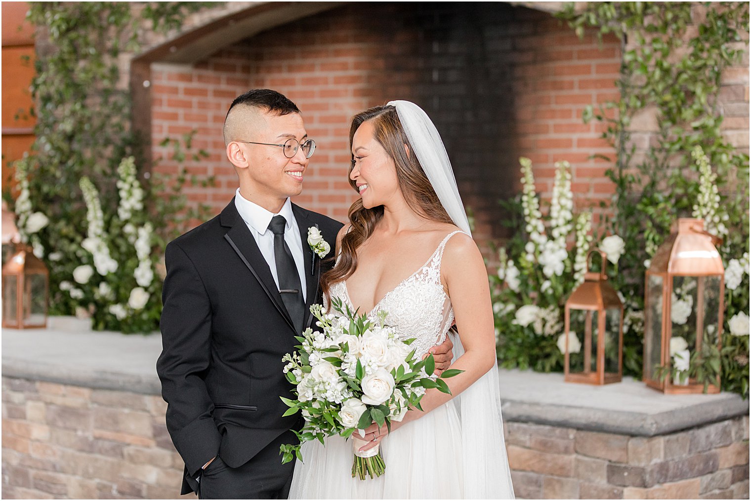 bride and groom smile together by fireplace at The Lodge at Stirling Ridge