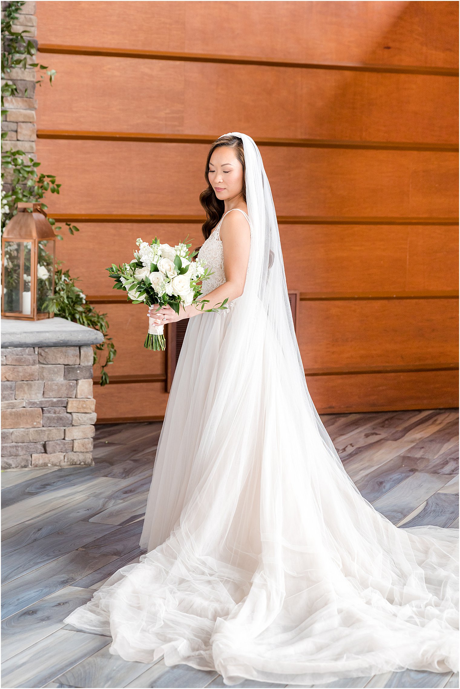 bride stands with bouquet looking over her shoulder
