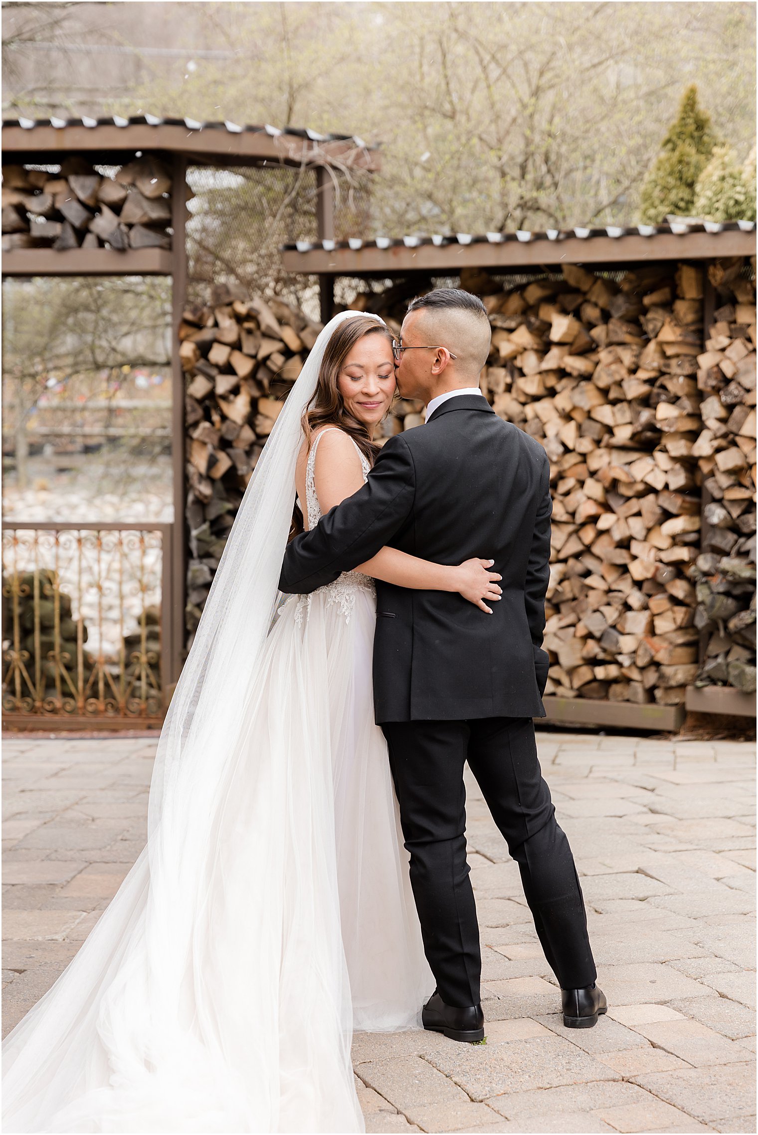 newlyweds hug by woodpile 