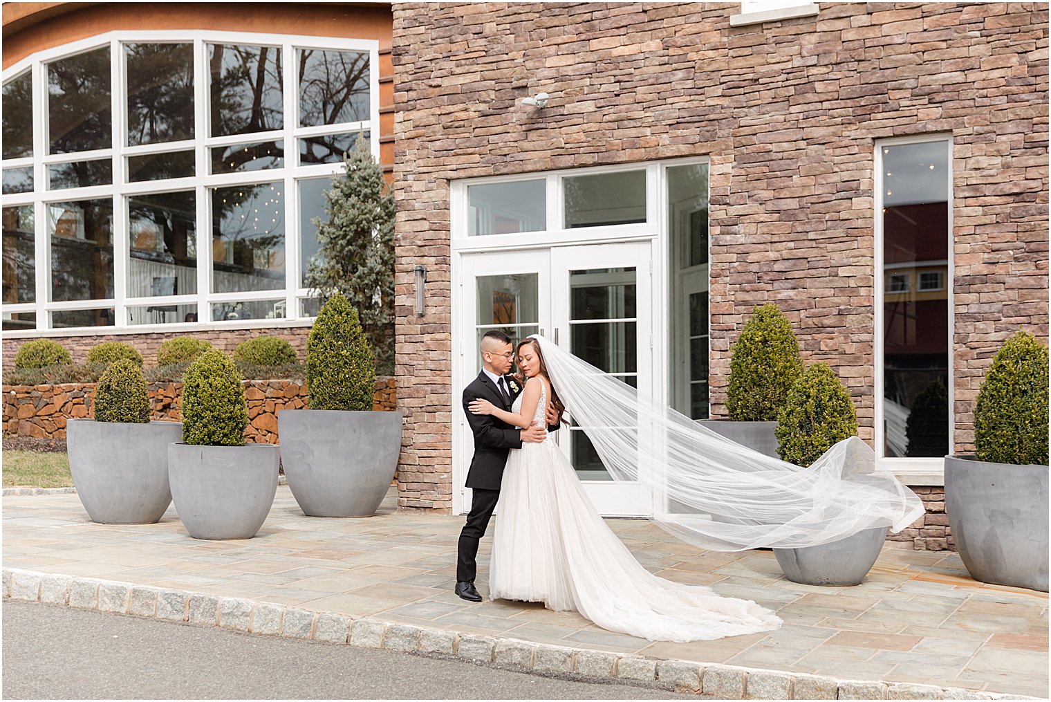 bride and groom hug outside stone wall at The Lodge at Stirling Ridge