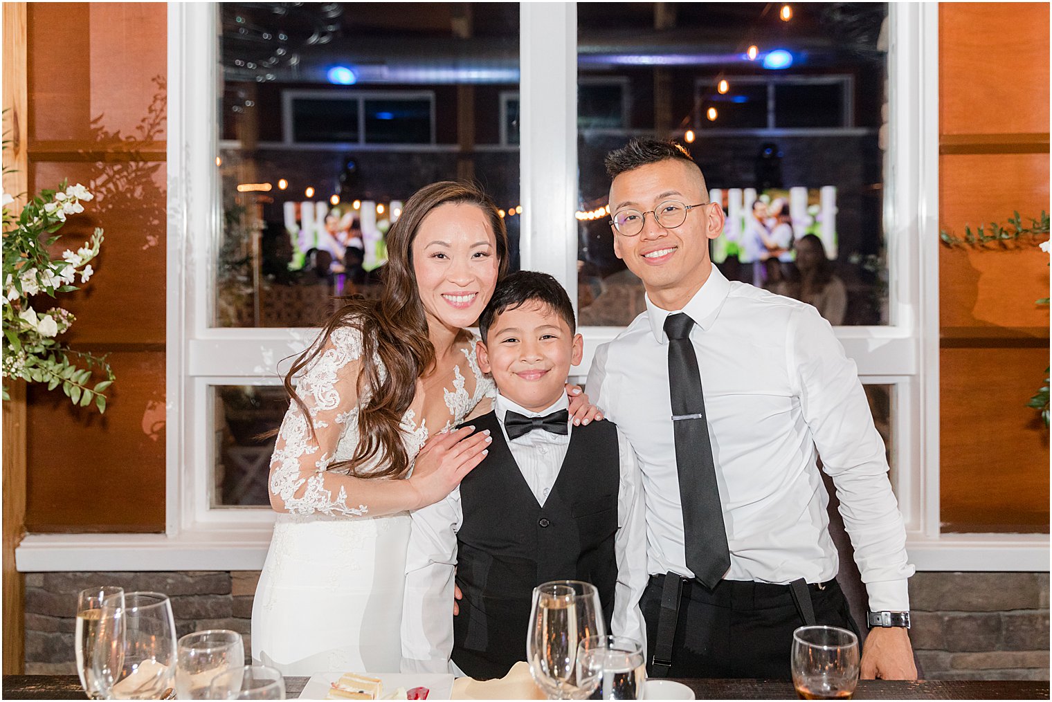 bride and groom pose with winner of game at reception