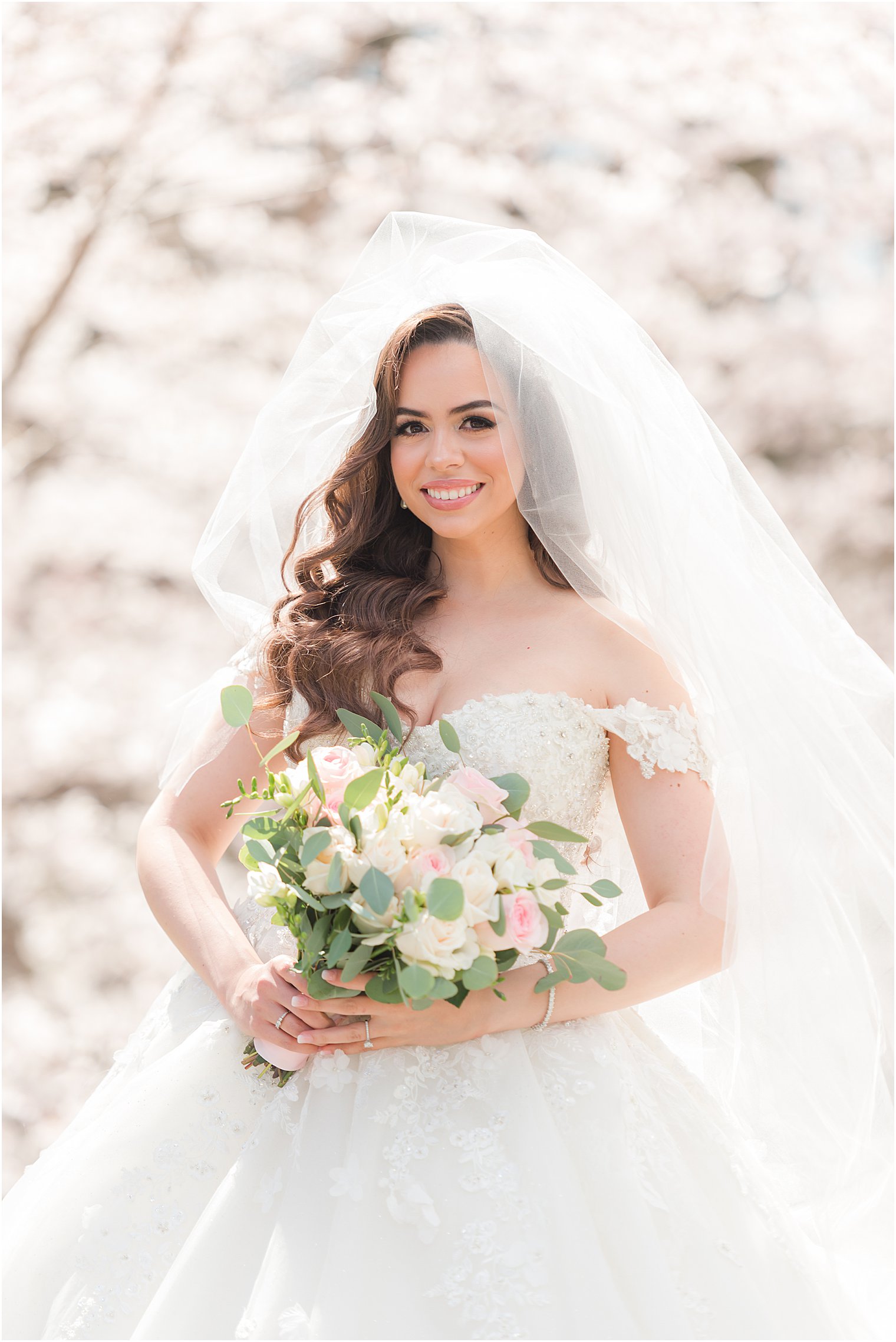 bride holds bouquet of pink and white flowers in Newark NJ by cherry blossoms 