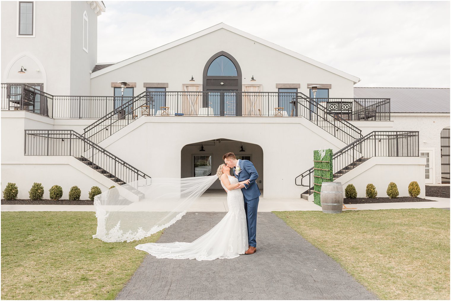 bride and groom kiss while wind blows veil at Renault Winery in Egg Harbor Township, NJ