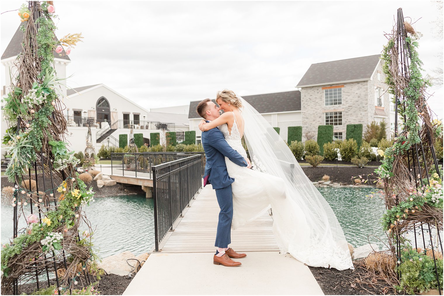 groom lifting bride and kissing her on bridge in front of Renault Winery in Egg Harbor Township, NJ