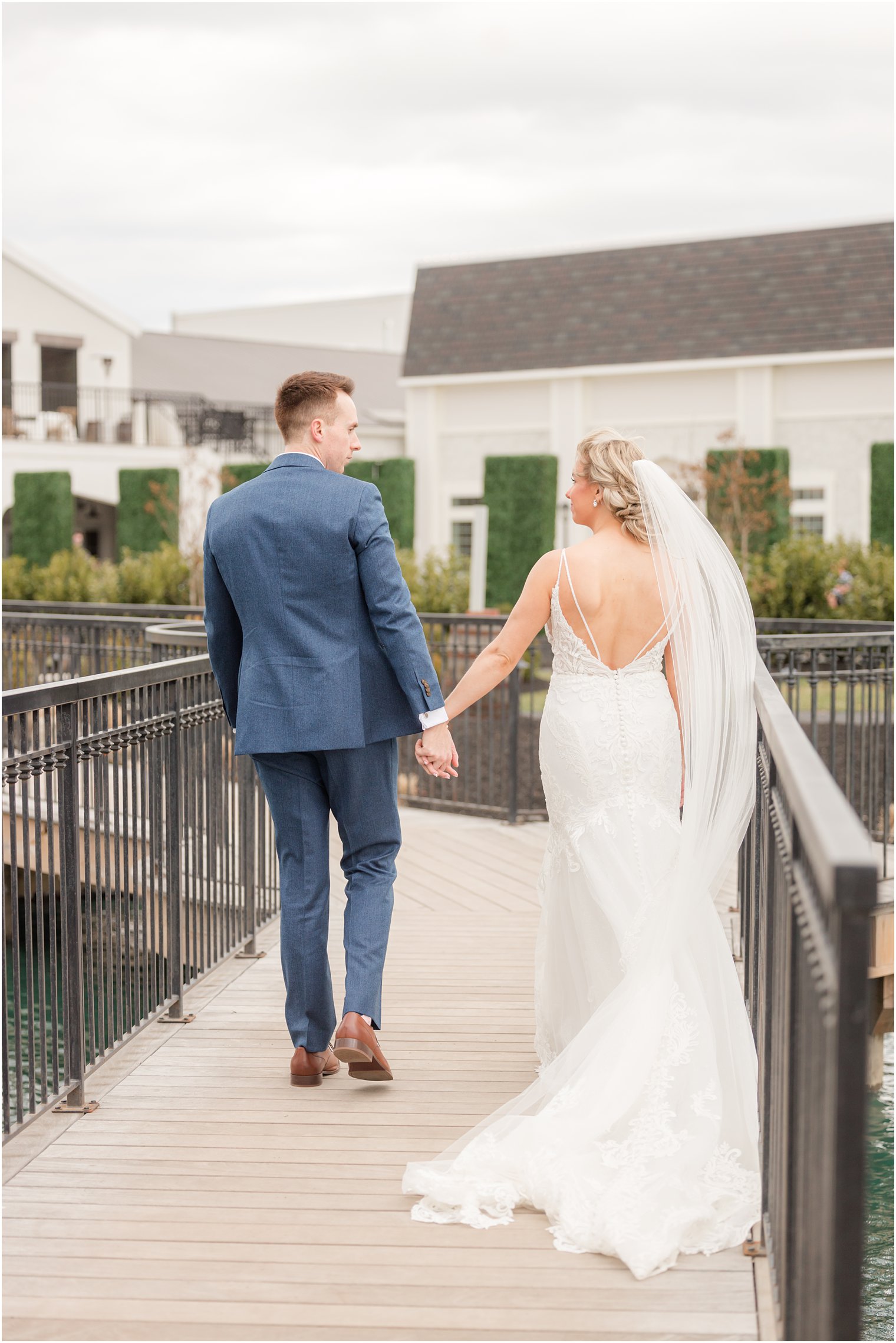 bride and groom walking to ceremony on bridge at Renault Winery in Egg Harbor Township, NJ