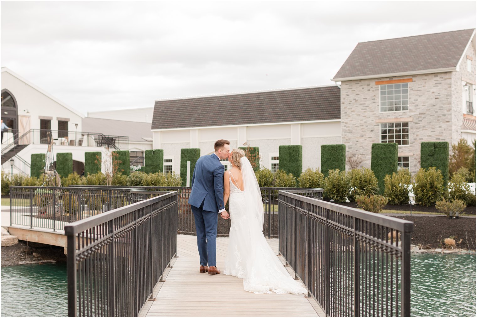 bride and groom kissing on bridge in front of Renault Winery in Egg Harbor Township, NJ