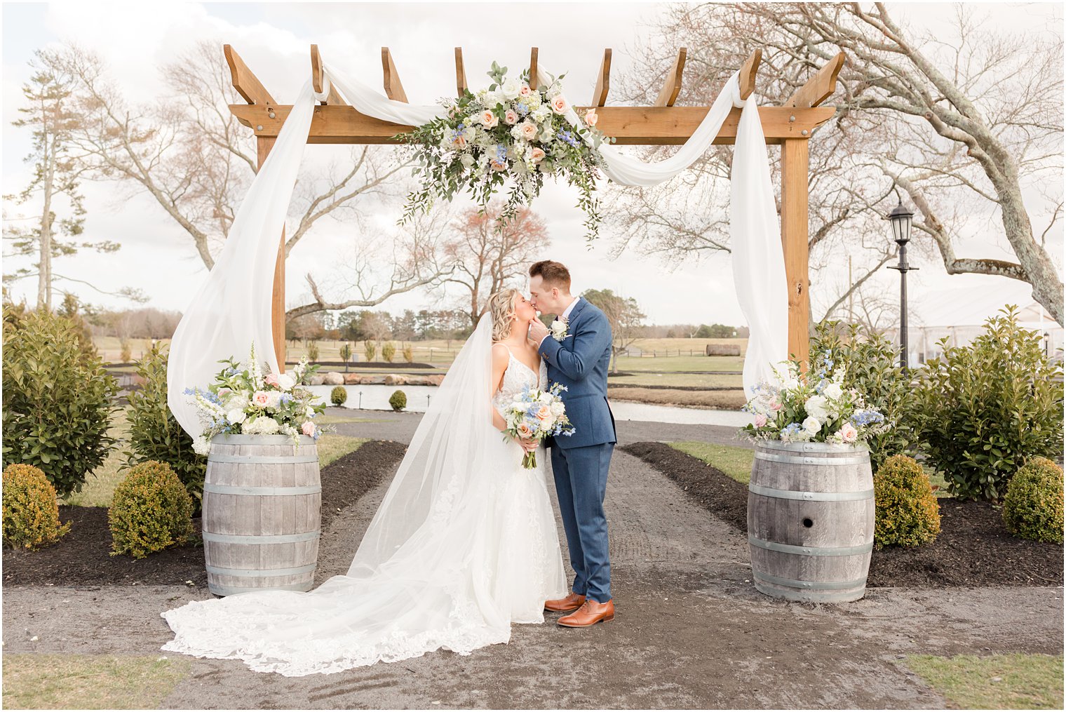 bride and groom under arch decorated with florals by Betinas