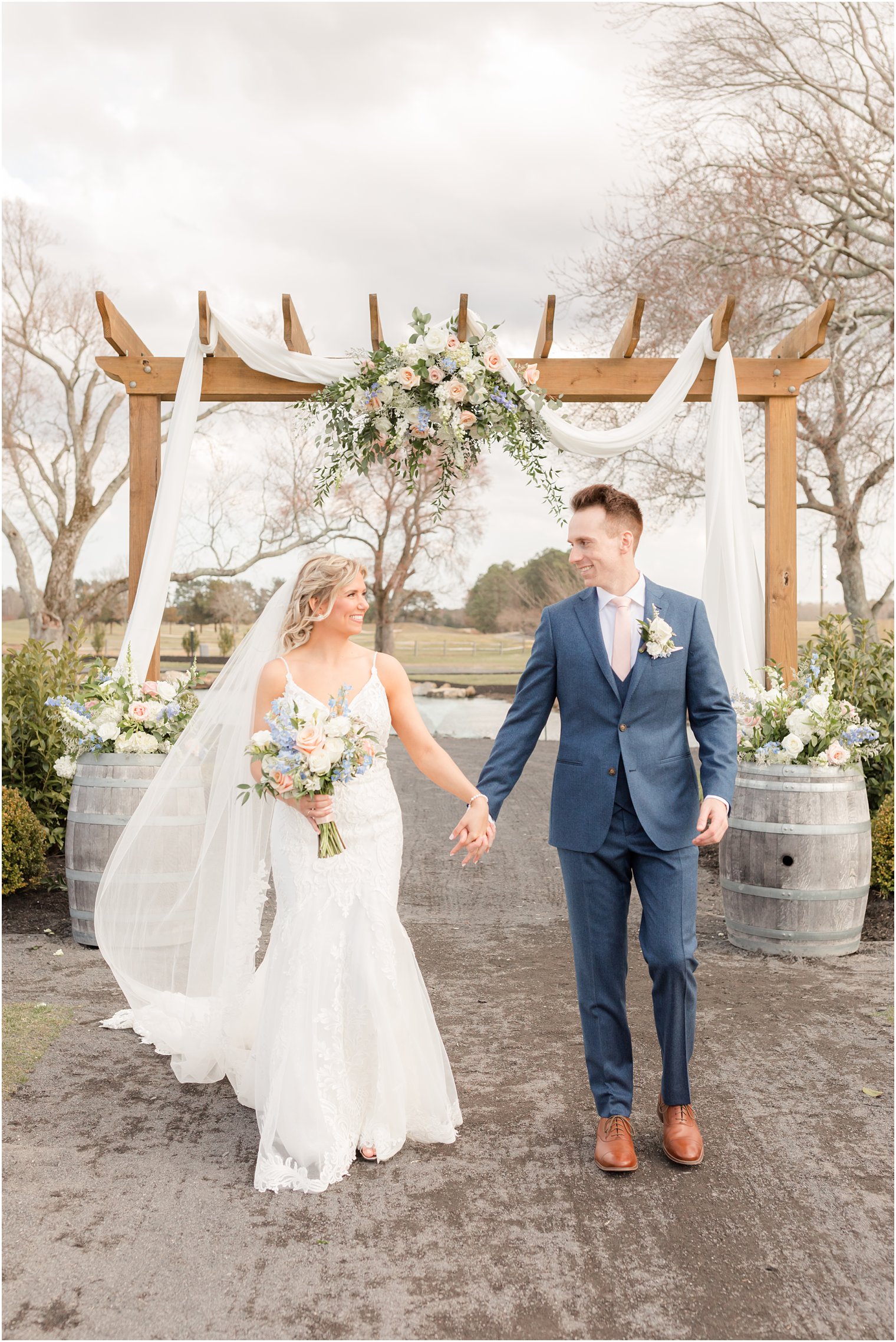 bride and groom walking under arch decorated by Betinas