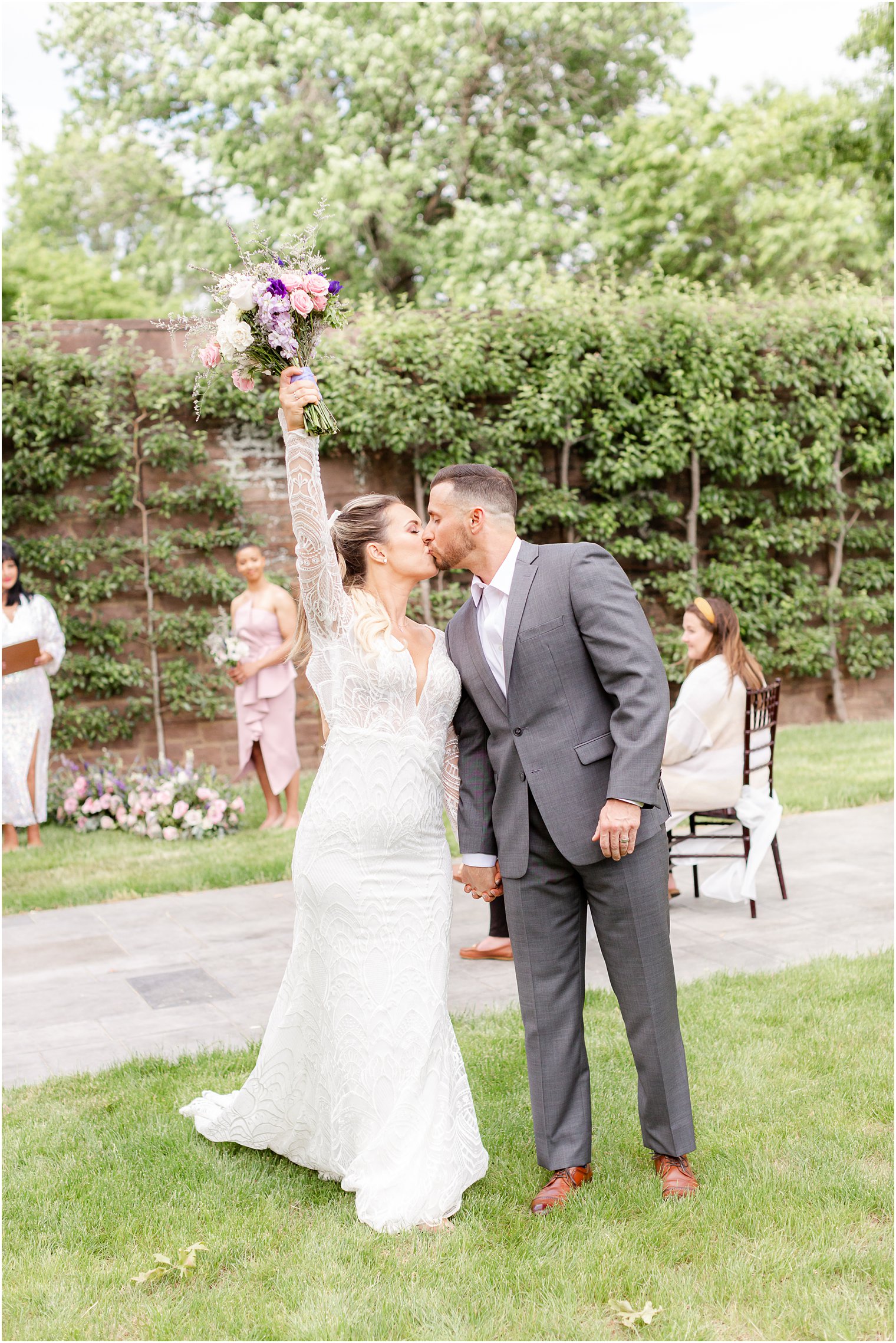 bride kisses groom while holding bouquet in air during ceremony in Tyler Gardens 