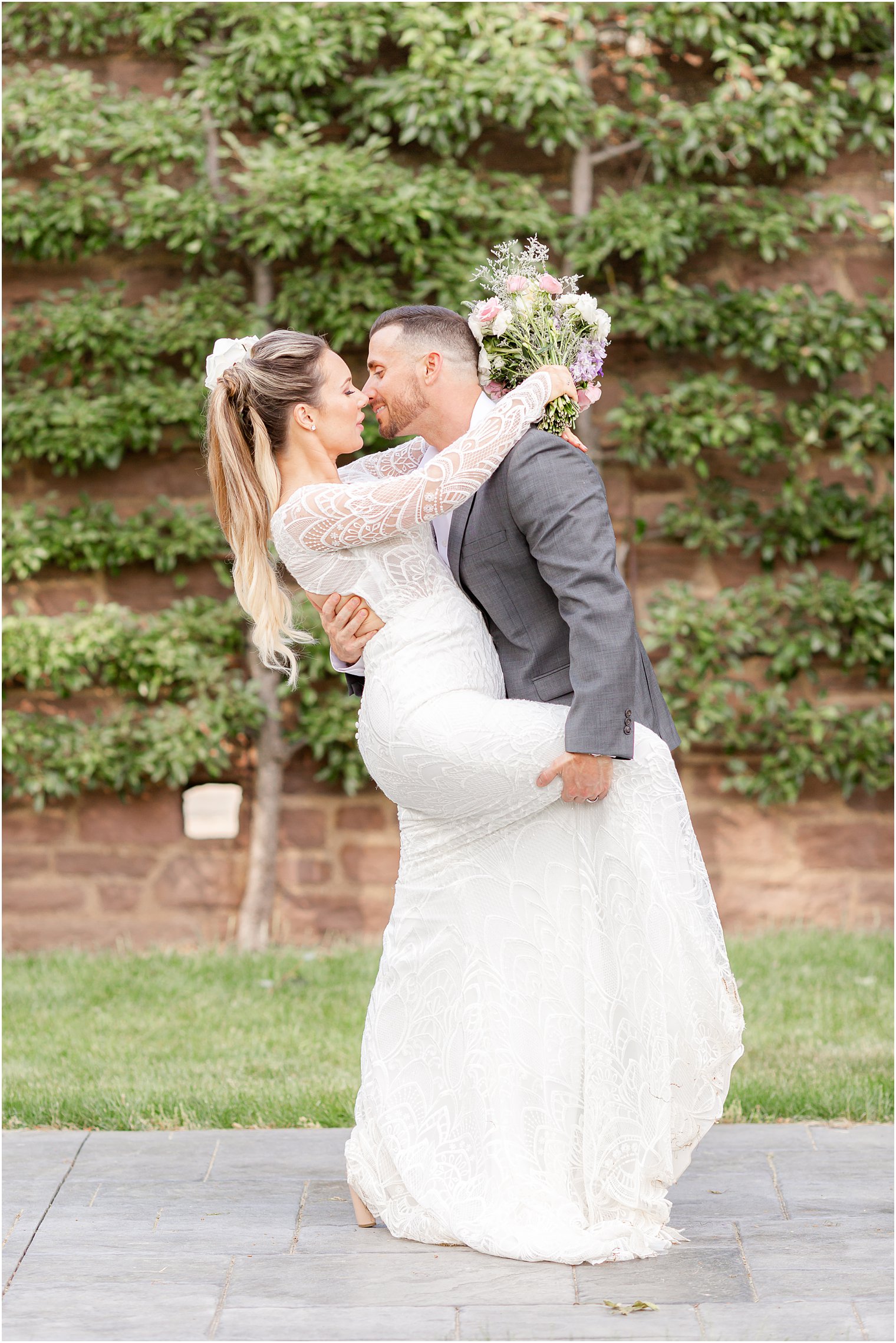 groom leans to kiss bride holding her leg up against him