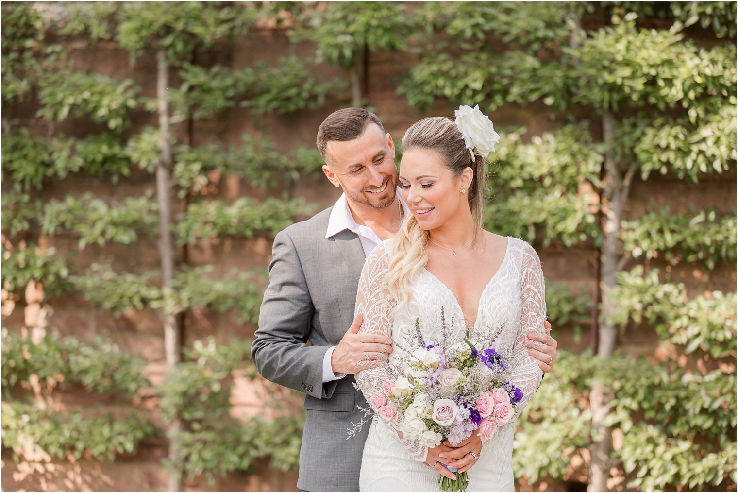 groom stands behind bride smiling at her during Croatian inspired minimony at Tyler Gardens