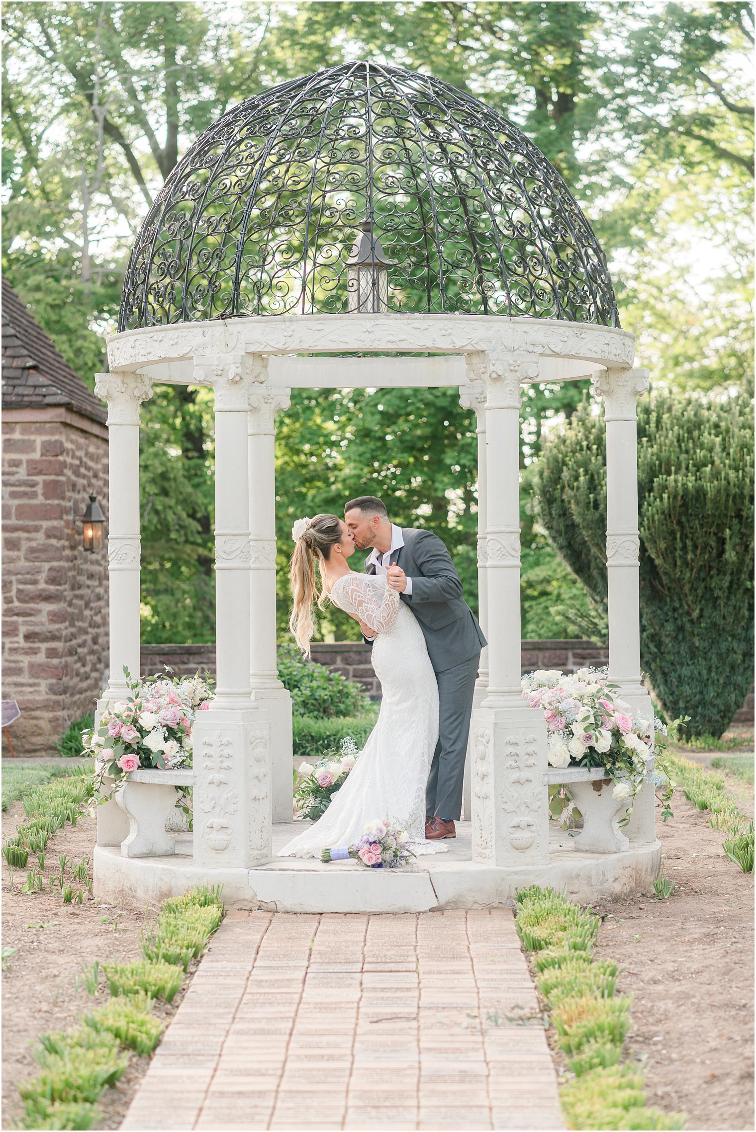bride and groom kiss in gazebo with wrought iron top at Tyler Gardens