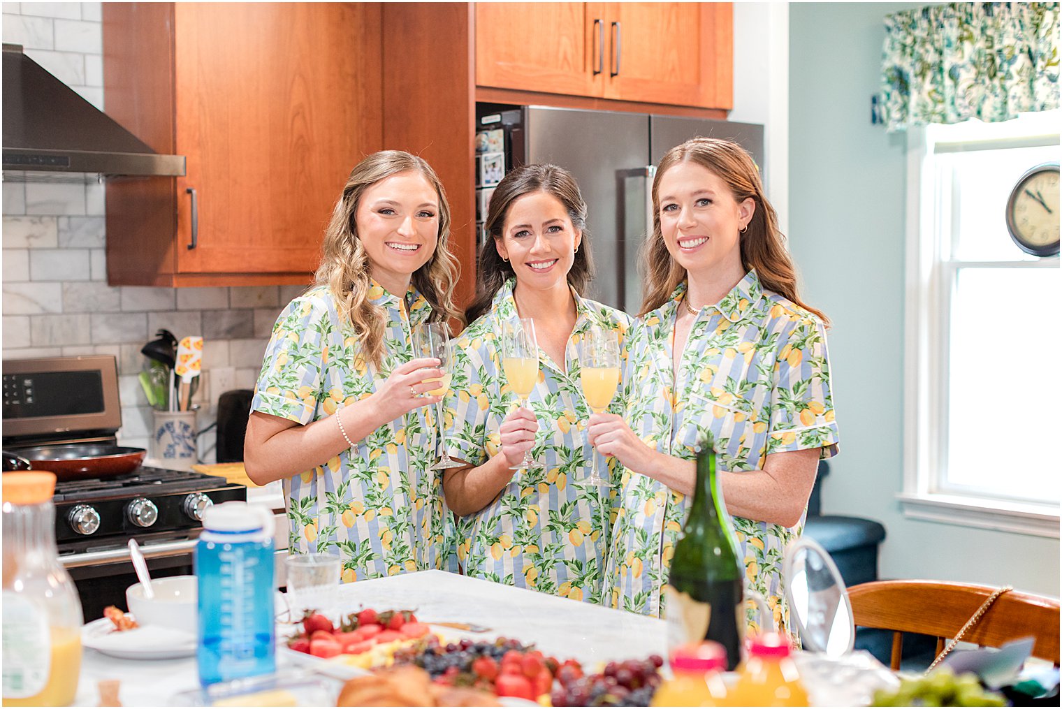 bridesmaids stand in kitchen with mimosas 