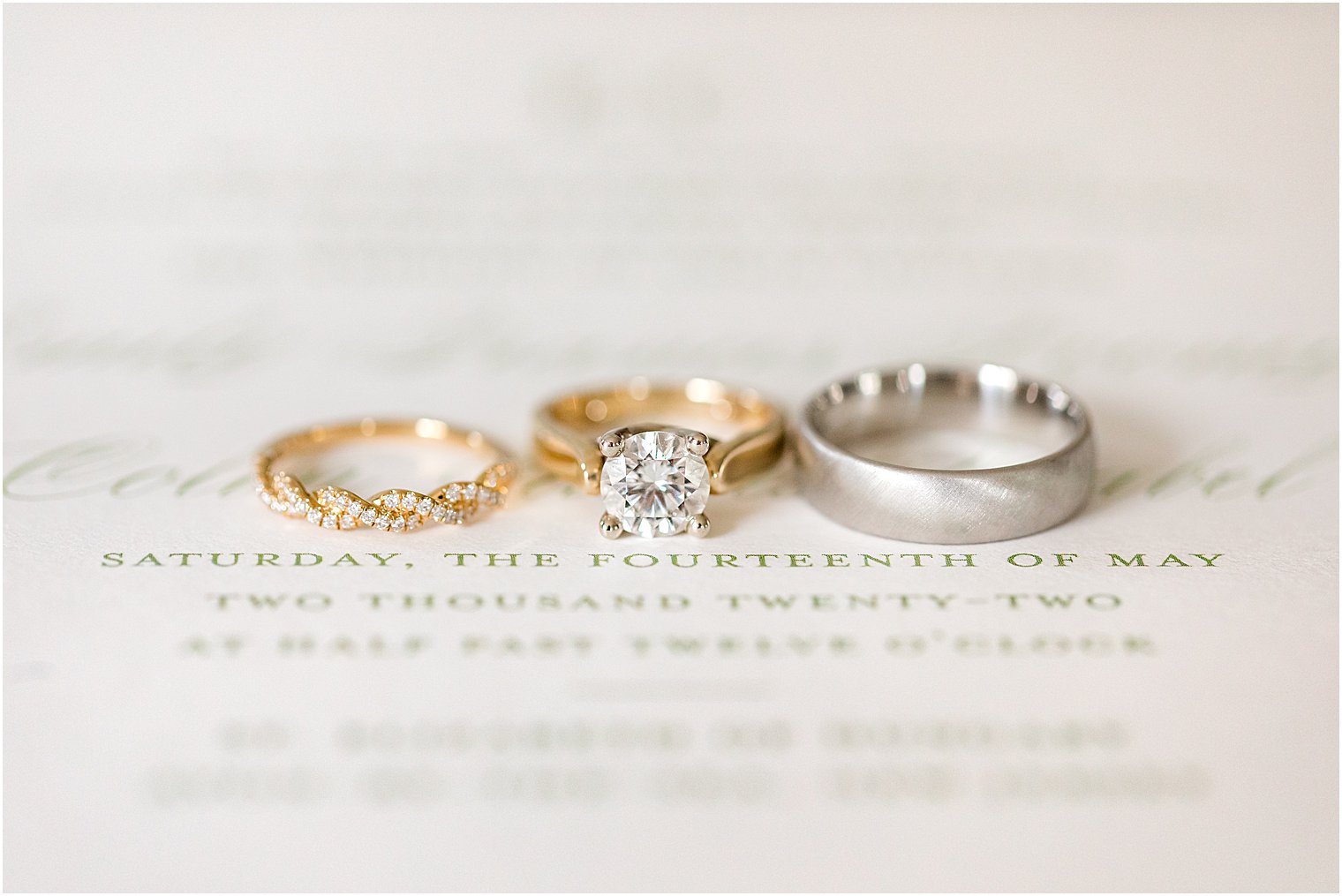 three wedding rings lay on invitation before NJ wedding