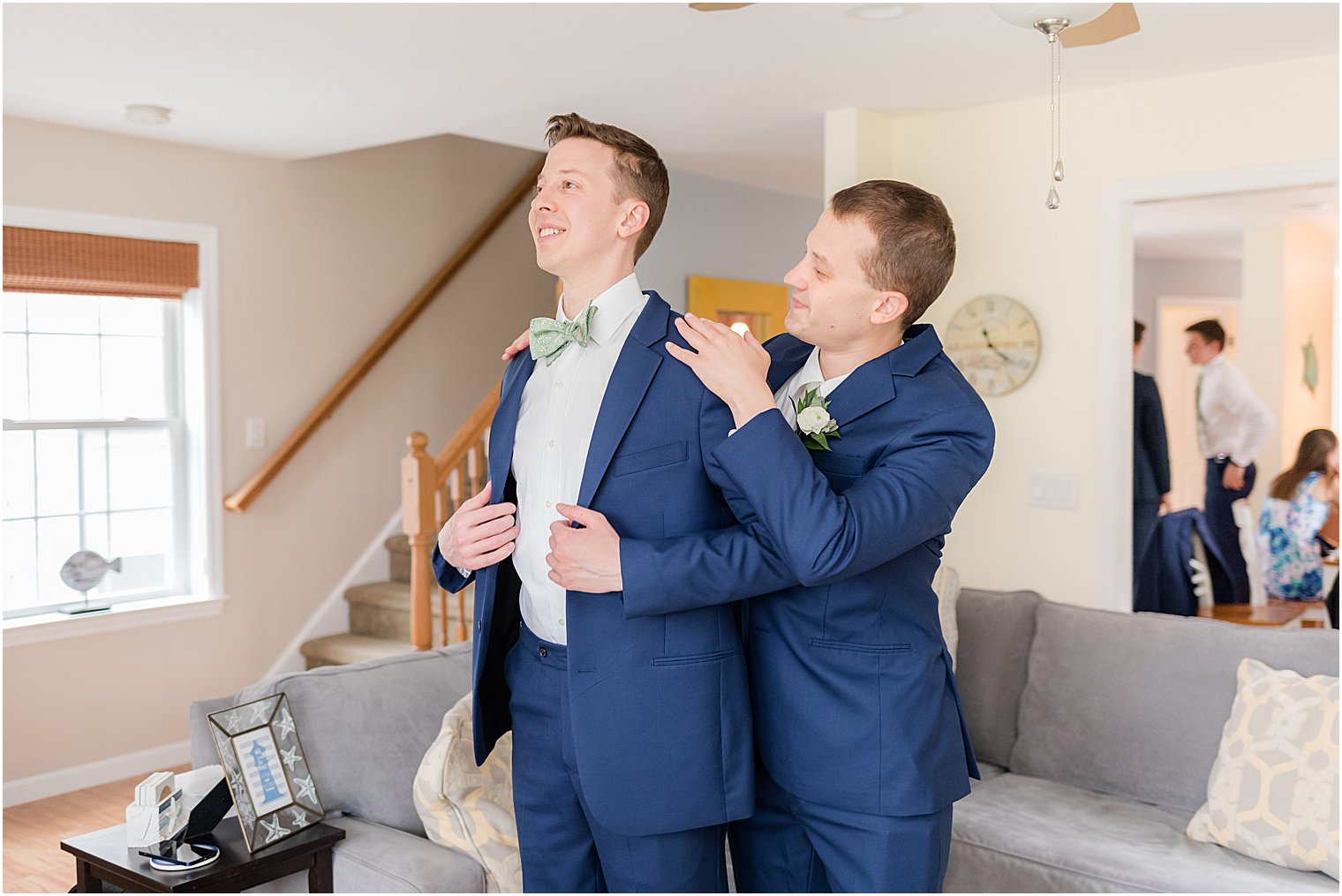 groomsman helps groom with suit jacket 