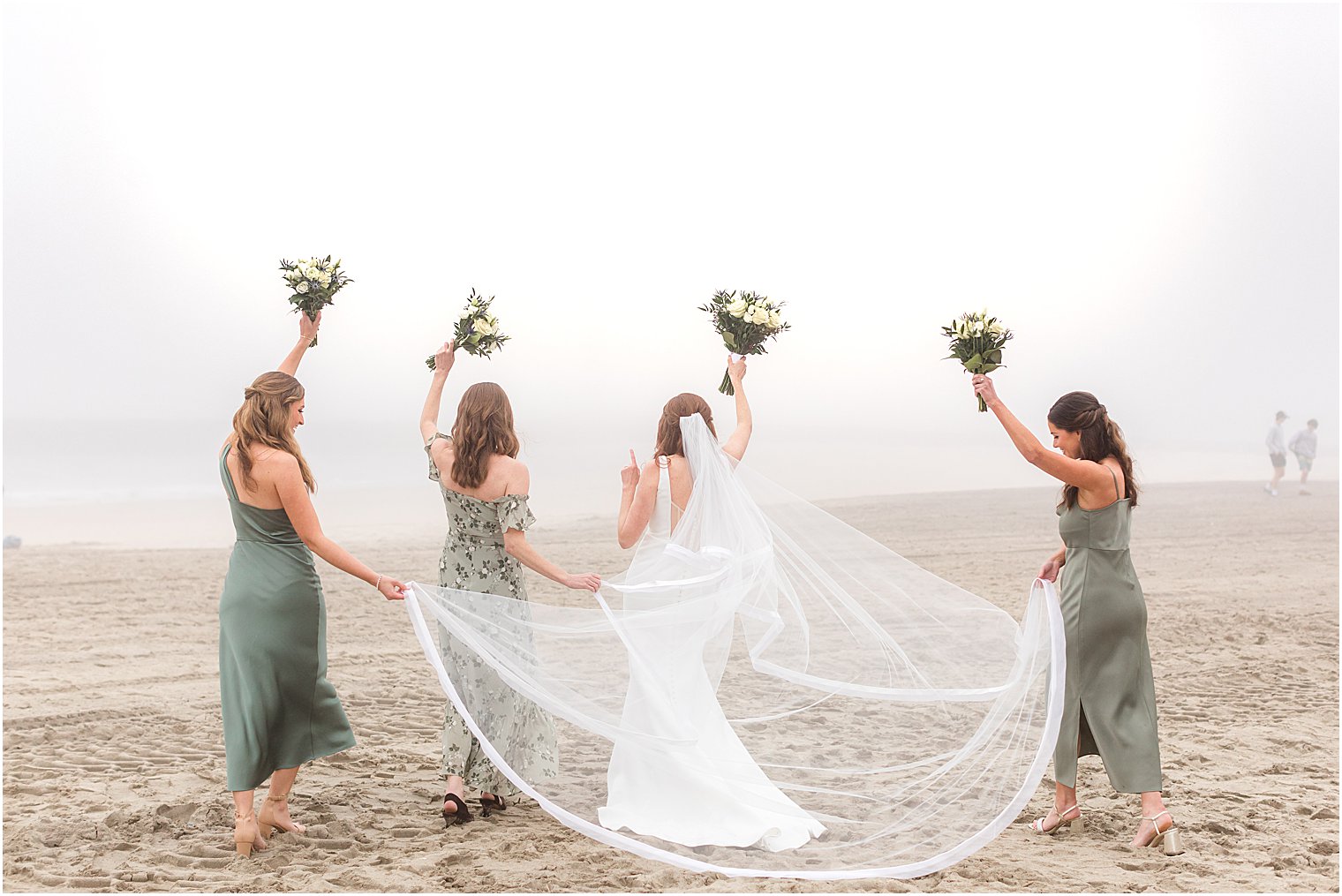 bride and bridesmaids raise bouquets in air