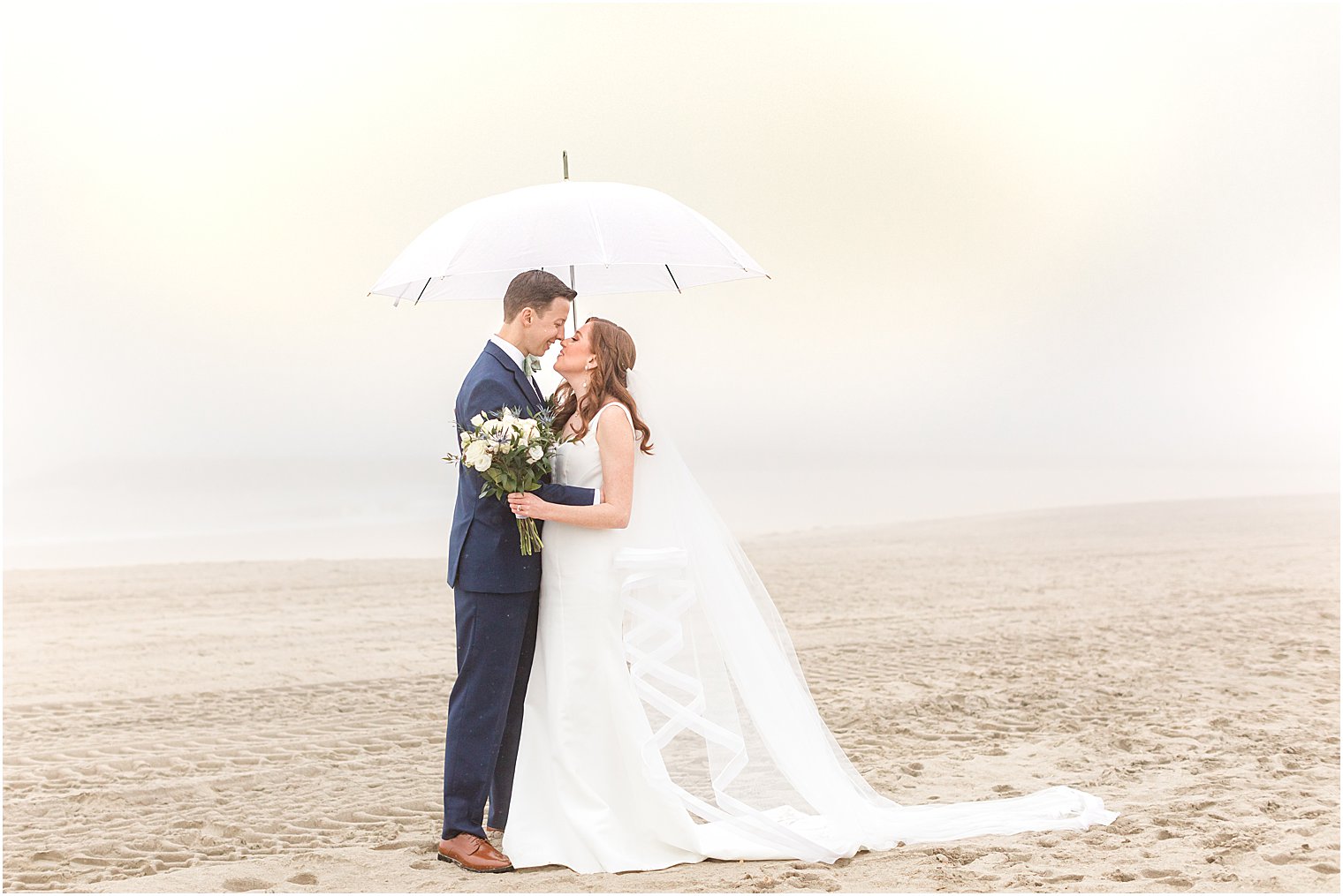 bride and groom pose under umbrella on rainy wedding day