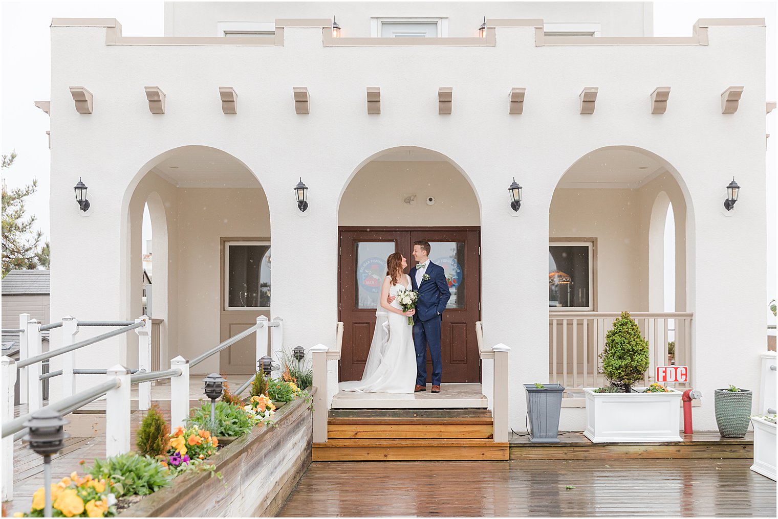 couple stands on steps at Belmar Fishing Club