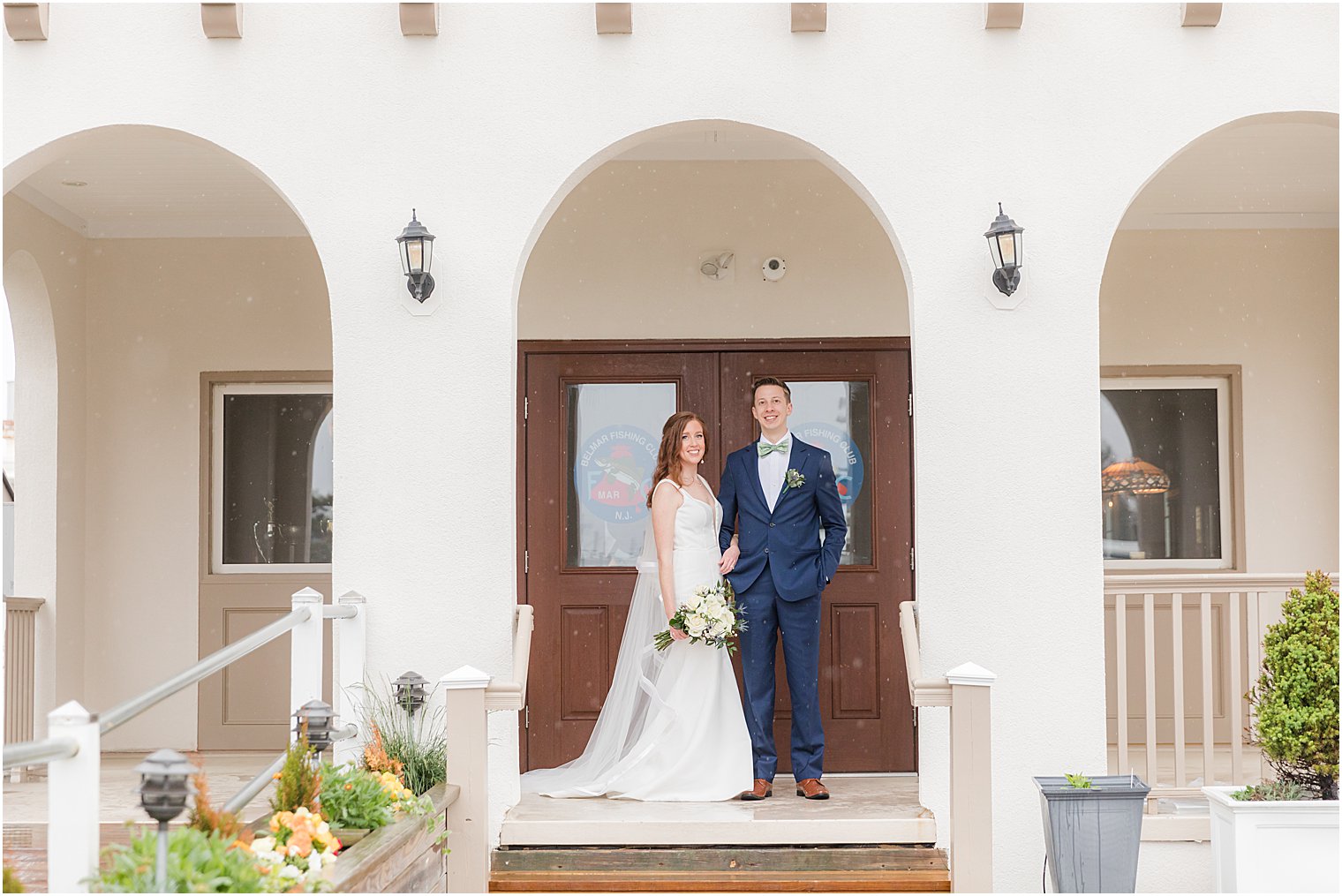 bride and groom pose under white archway at Belmar Fishing Club