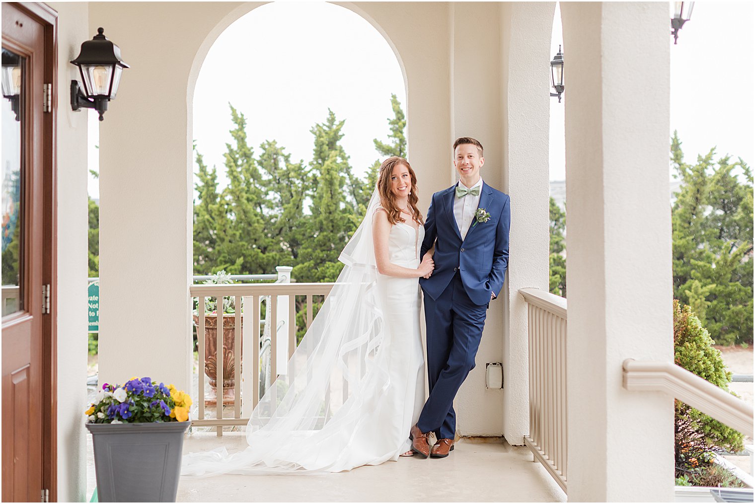 bride and groom lean against railing at Belmar Fishing Club