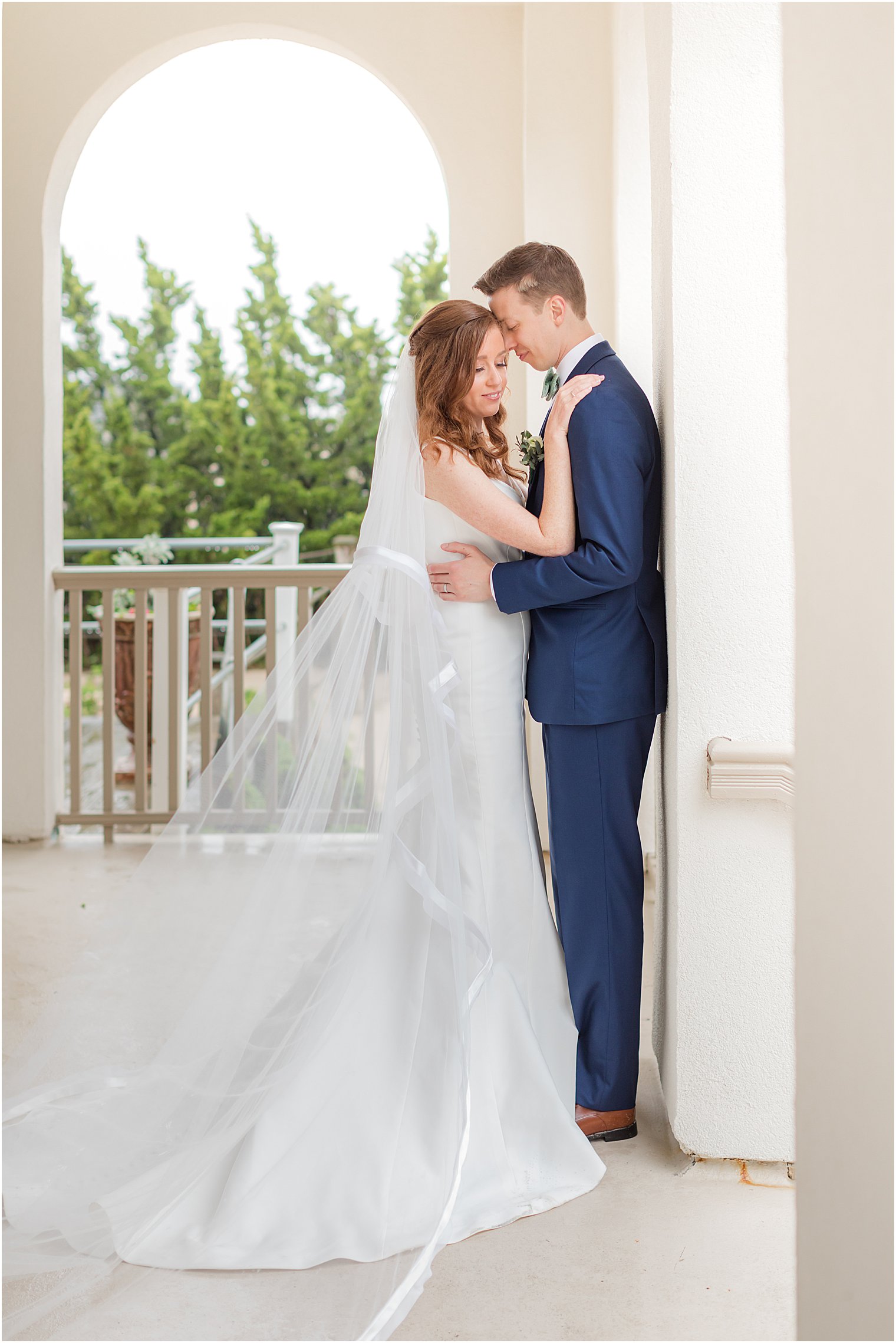 bride and groom hug against white column 