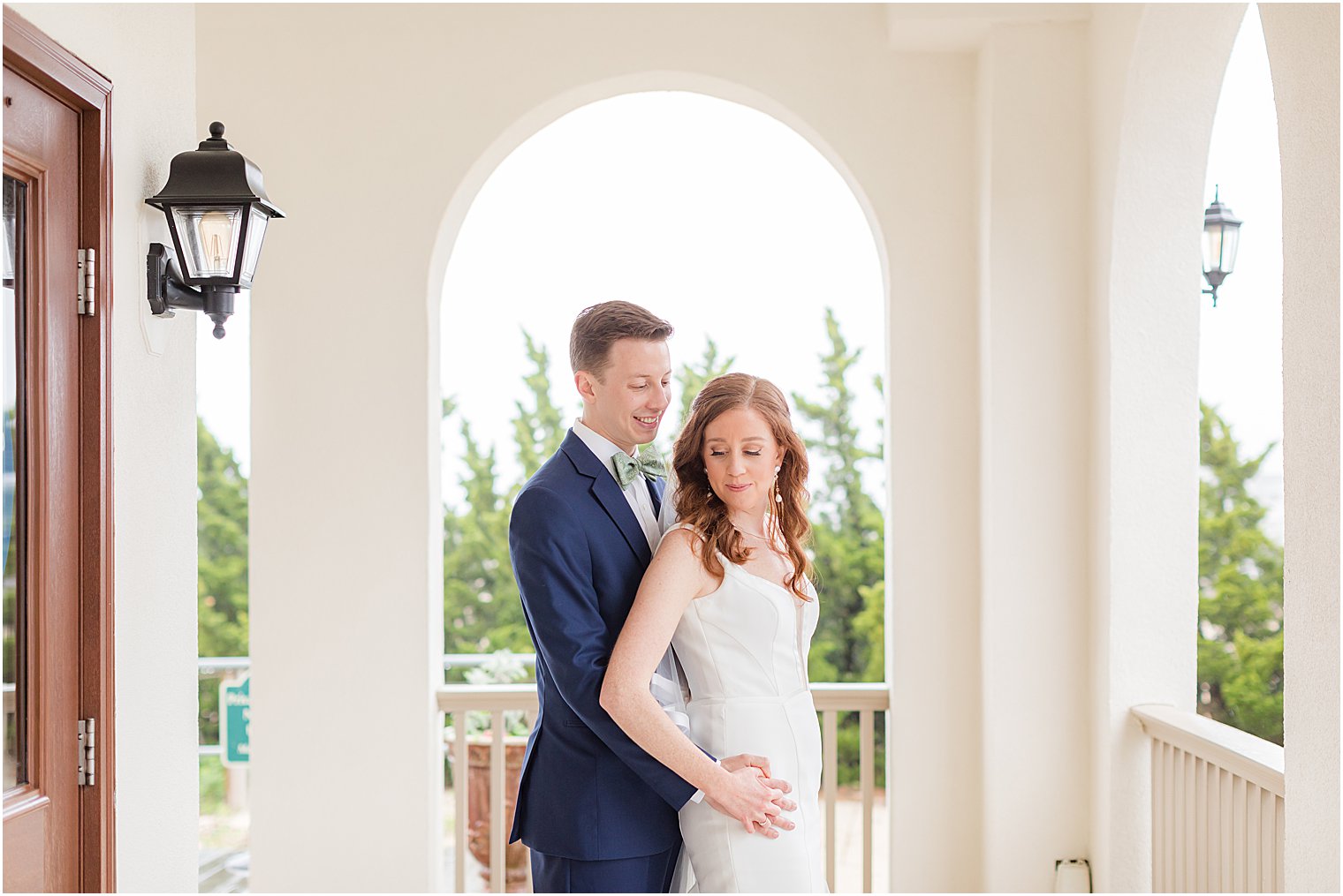 groom hugs bride's hips during Belmar Fishing Club wedding portraits 