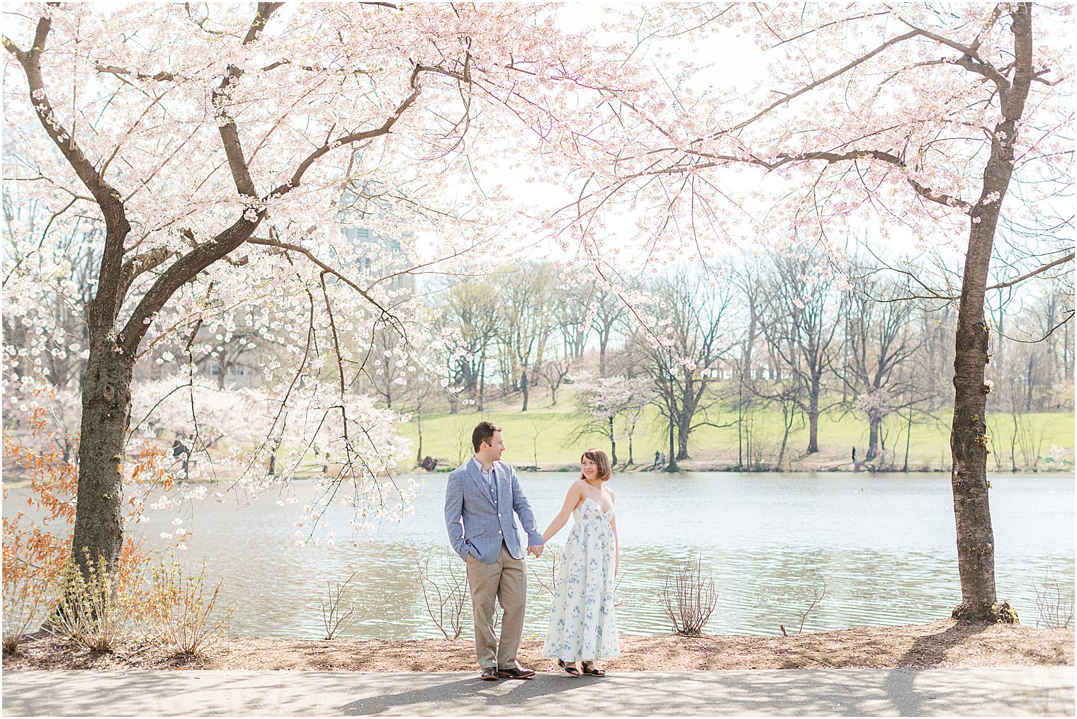 engaged couple holds hands walking through Branch Brook Park