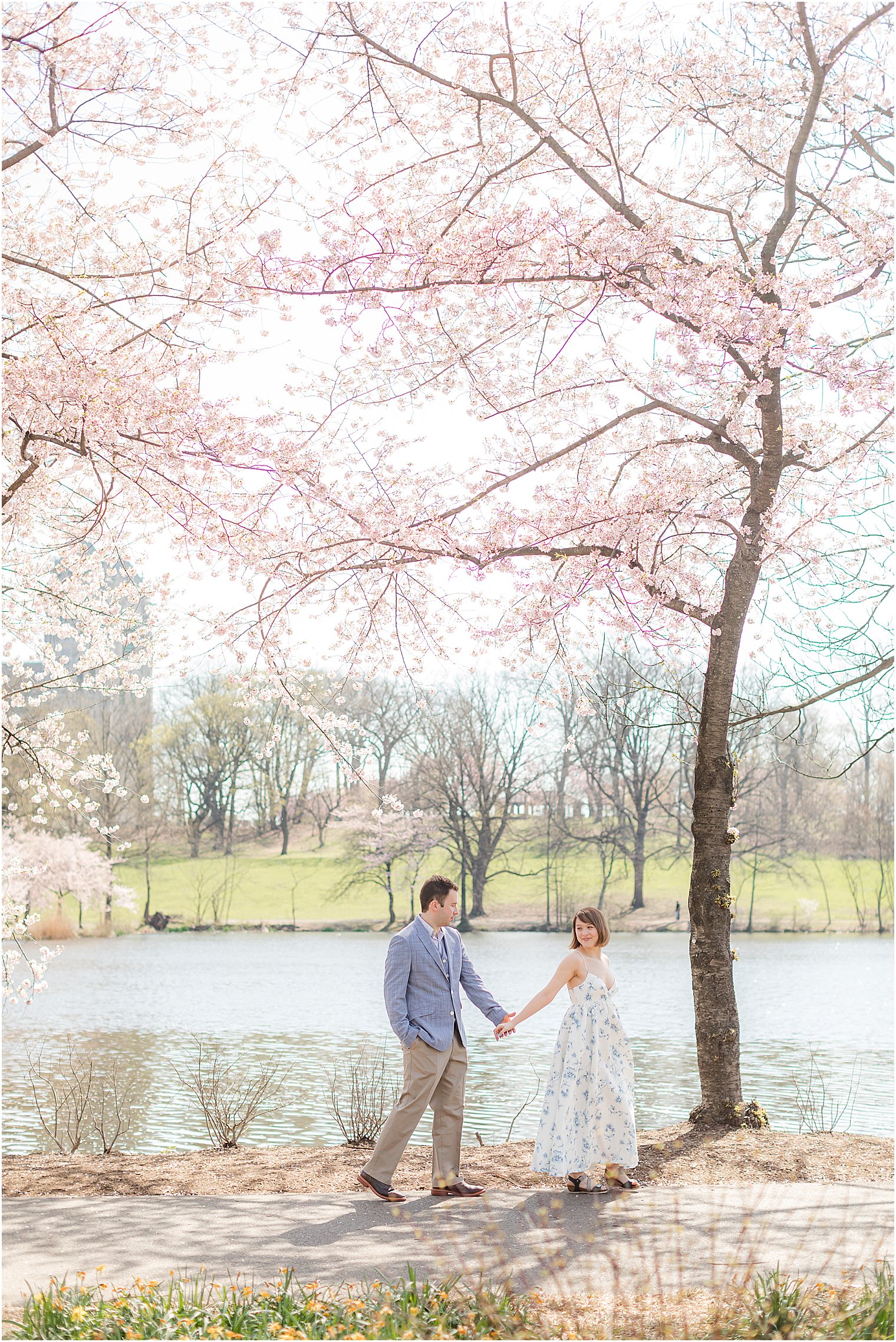 bride and groom hold hands walking in park