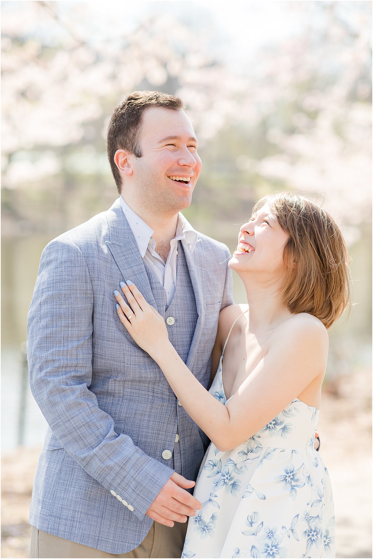 engaged couple laughs together during spring cherry blossom engagement session at Branch Brook Park