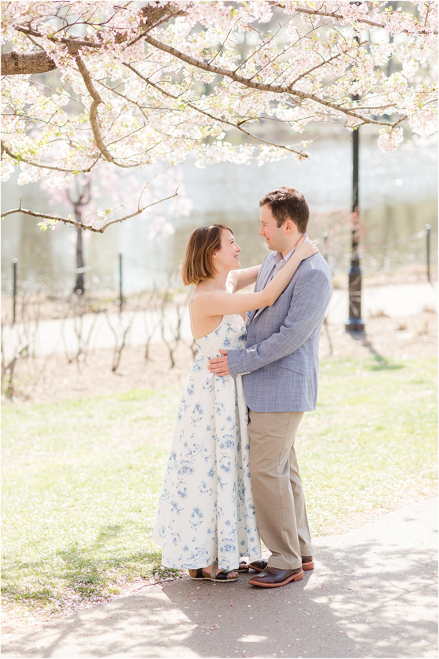 woman stands with arms around fiancé's neck during spring engagement session