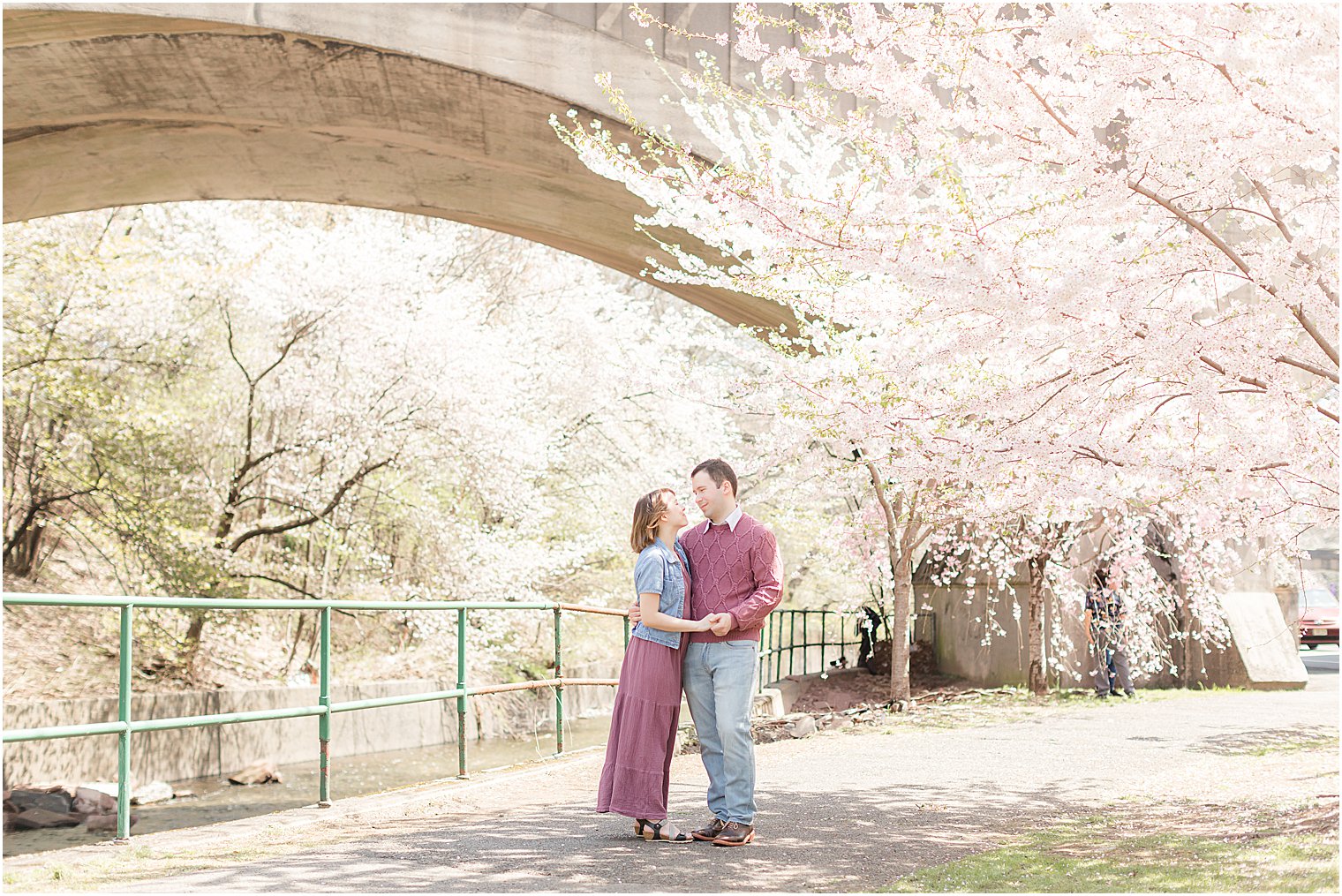 bride and groom smile together under bridge during spring engagement session in New Jersey