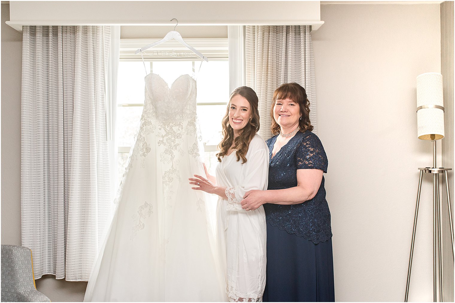 bride and mom admire wedding dress