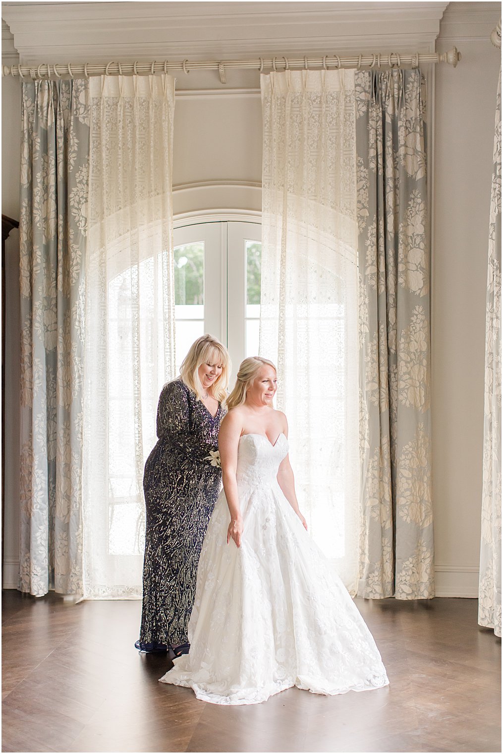 mom helping bride get on wedding dress on tips to include mom in wedding photos