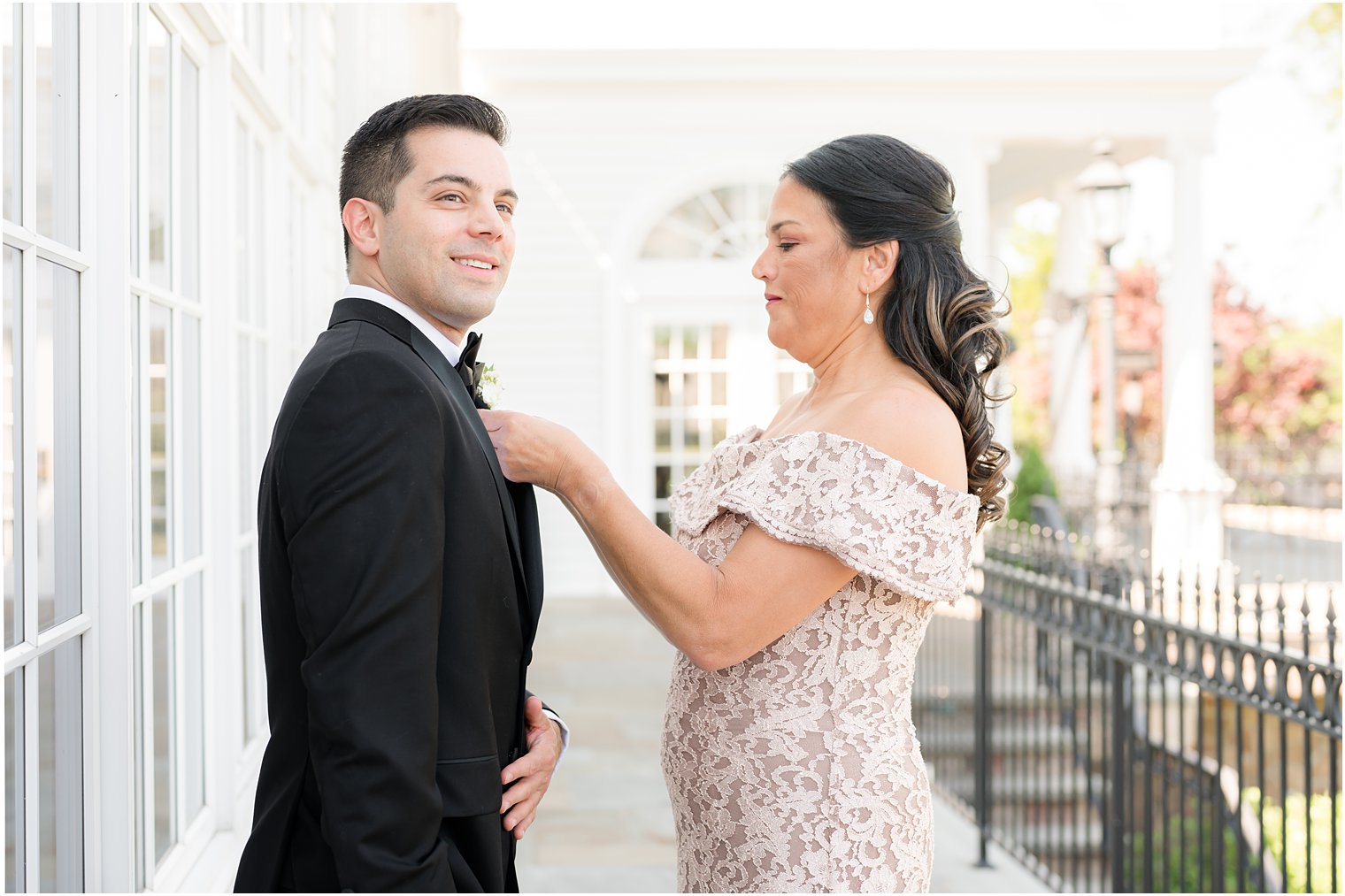 tips for including mom in wedding day photos: mom helping son with tie and boutonniere