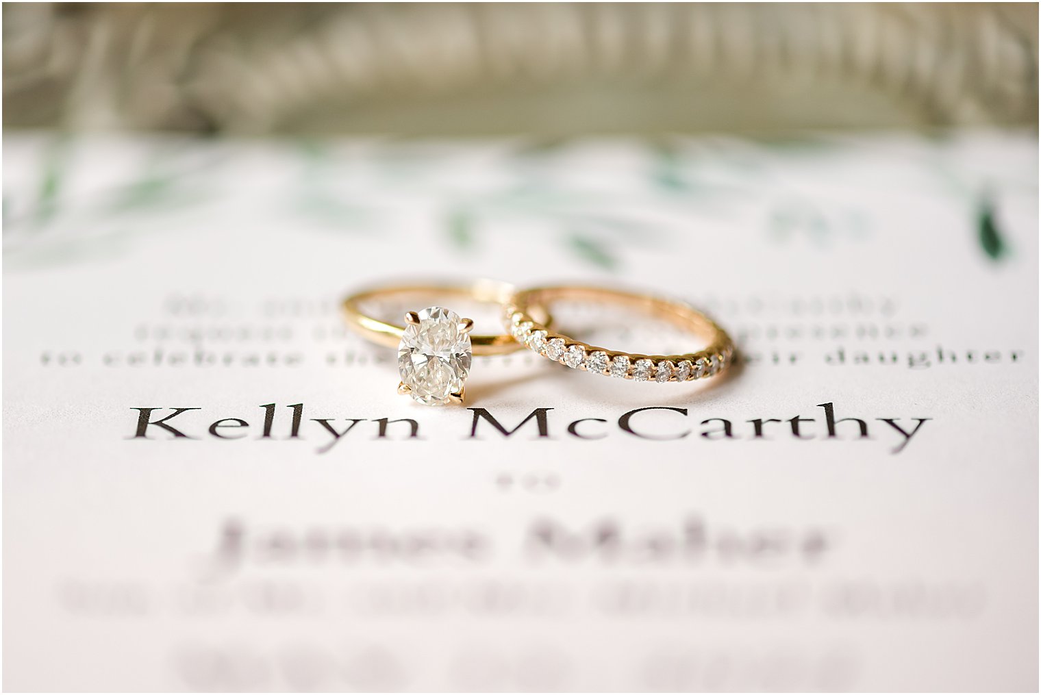 gold wedding bands sit on invitations from Minted