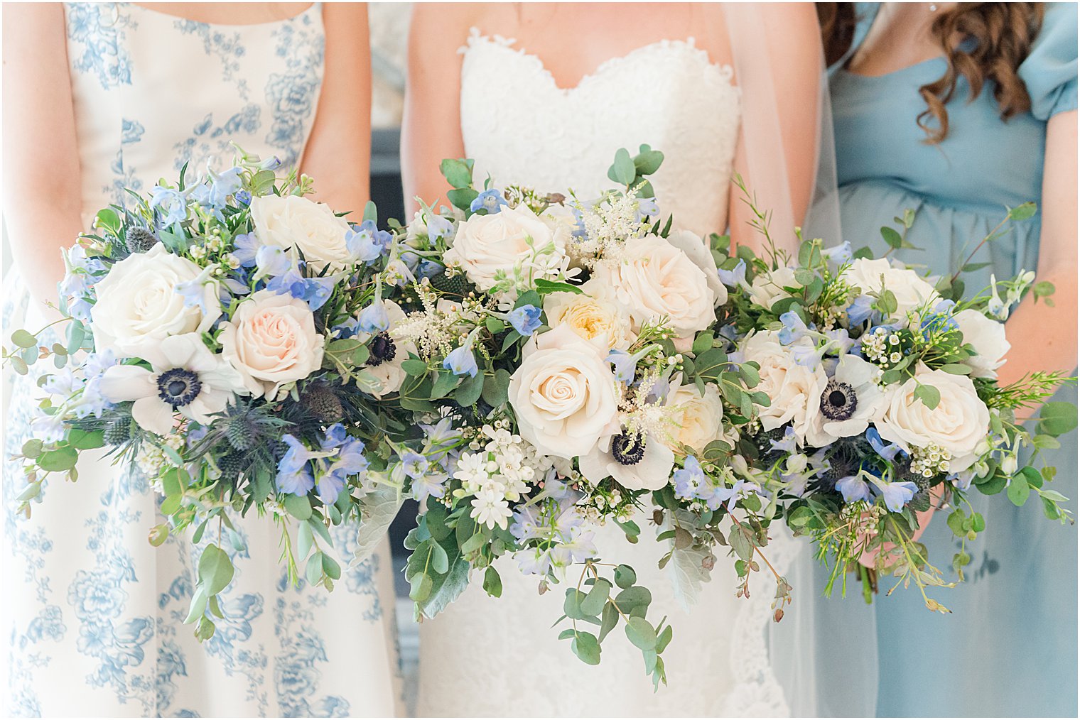 bride and bridesmaids hold bouquets with white and pink flowers