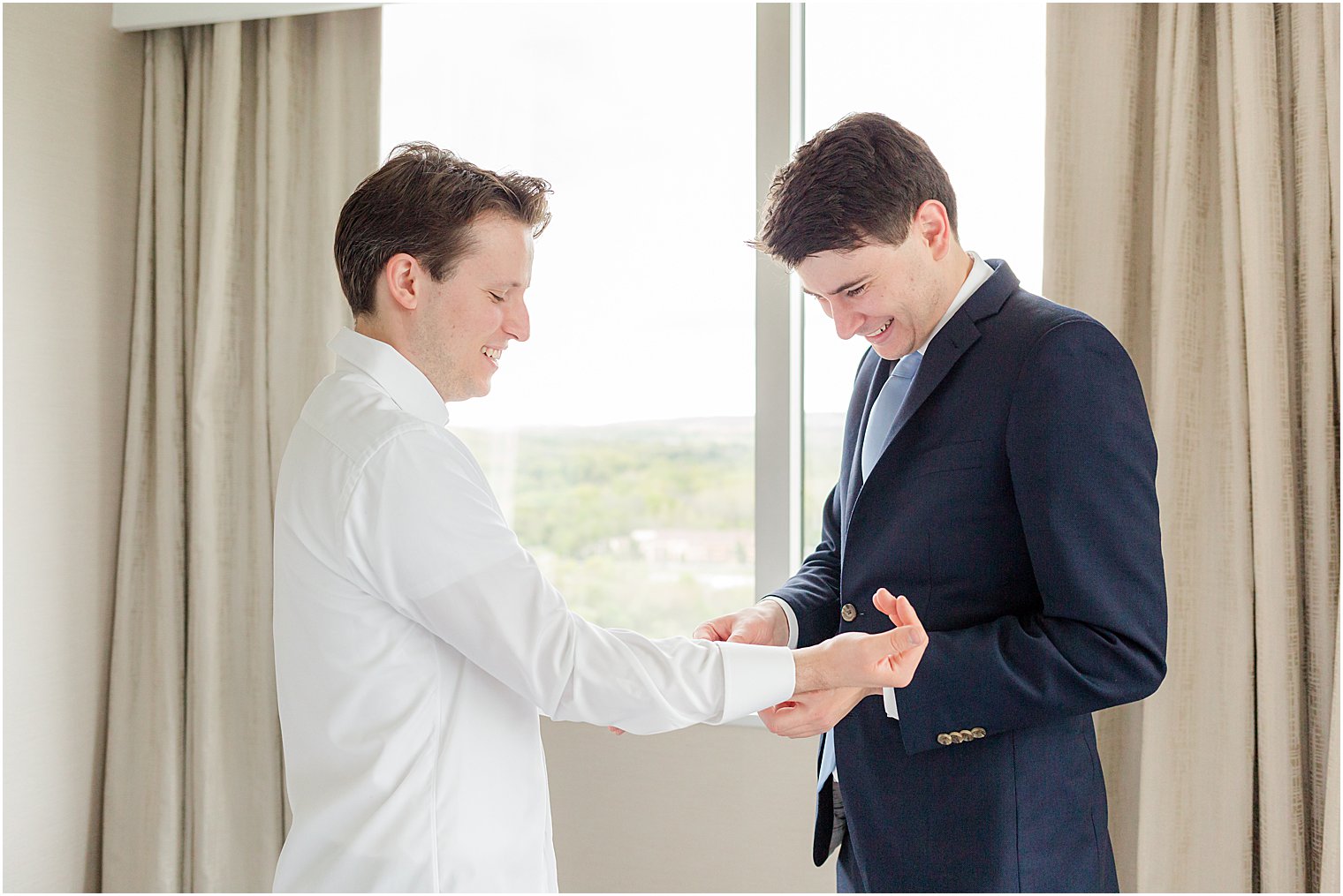 groomsman helps groom with cufflinks 