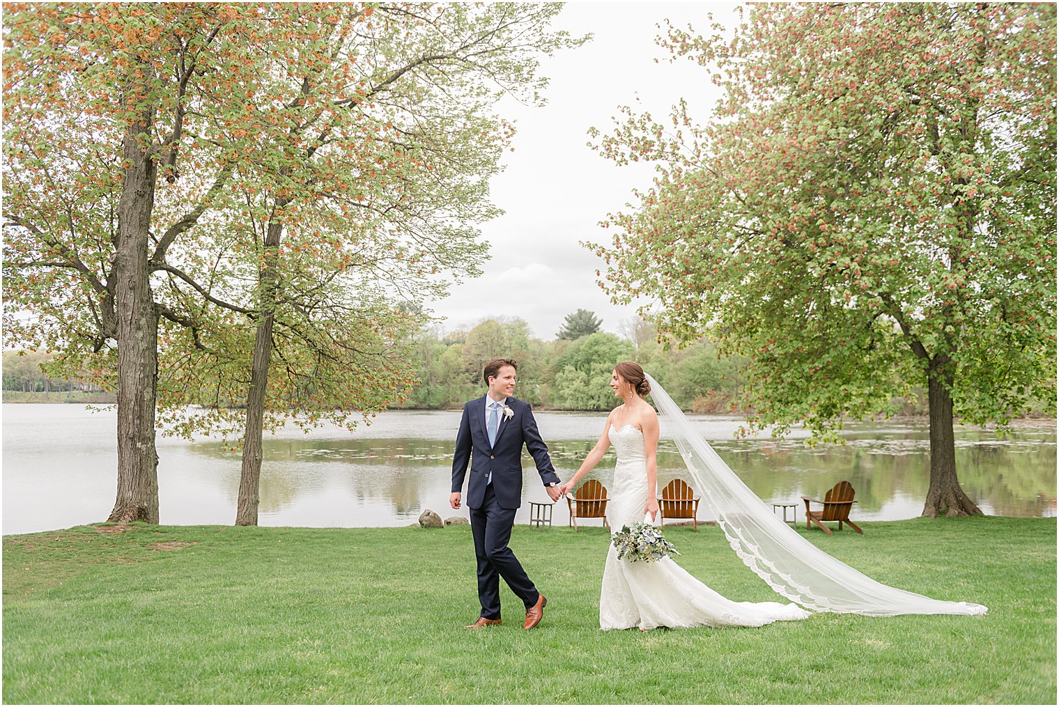 bride and groom hold hands walking across lawn